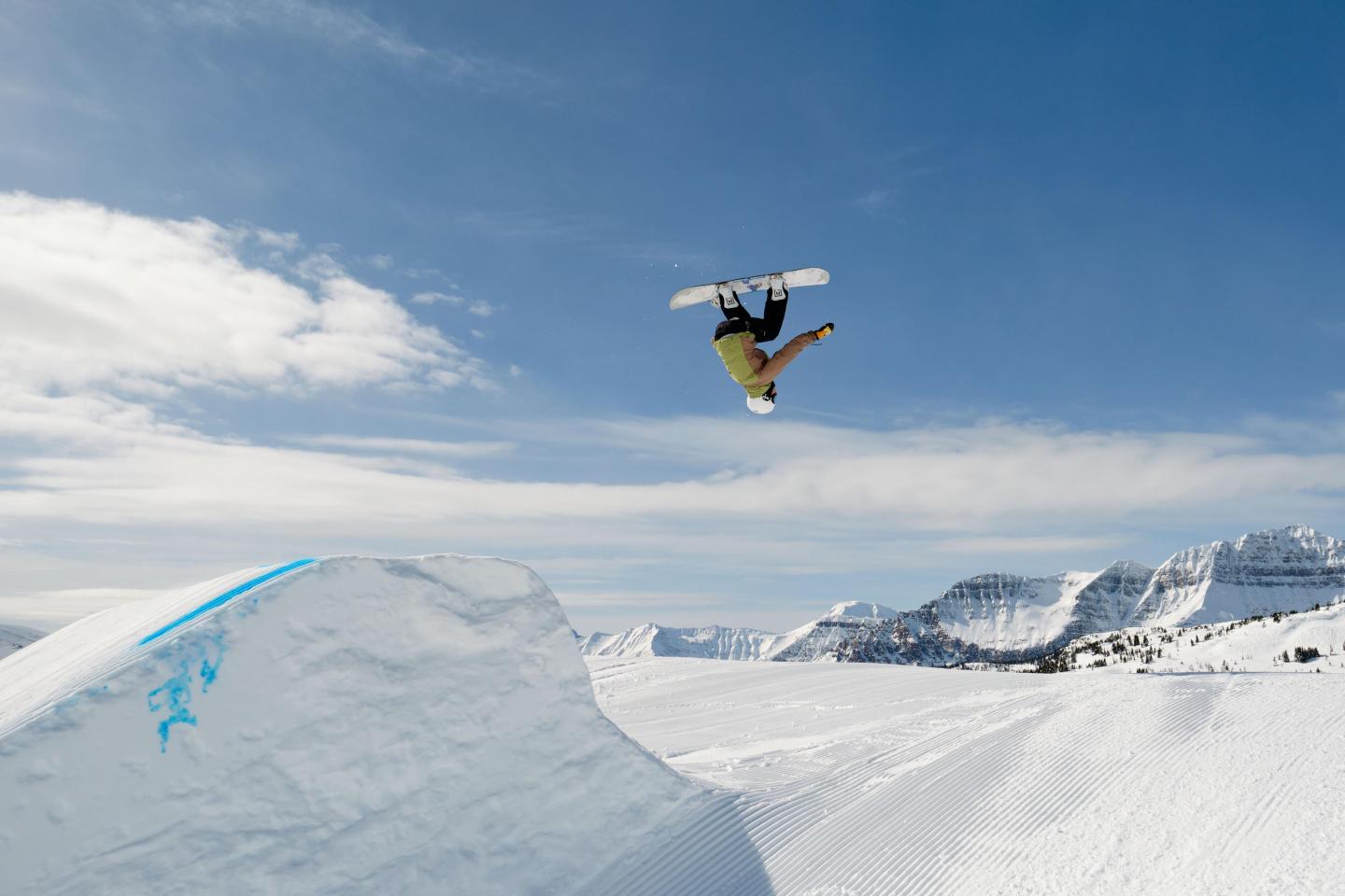 Snowboarder performing aerial trick on sunny day.