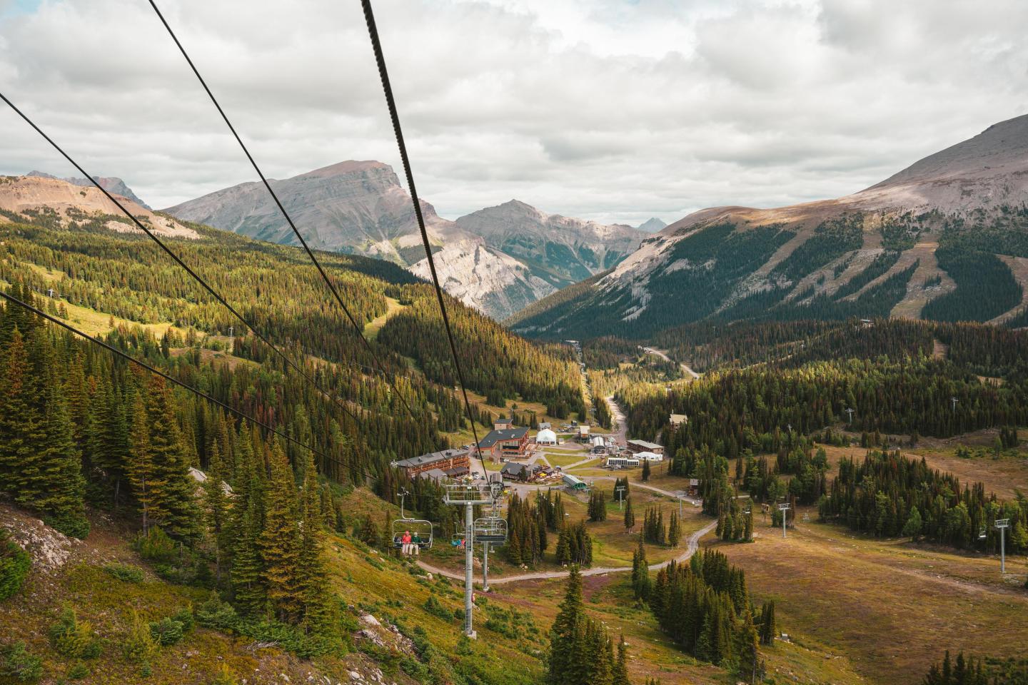 Mountain landscape with a ski lift and small village below.
