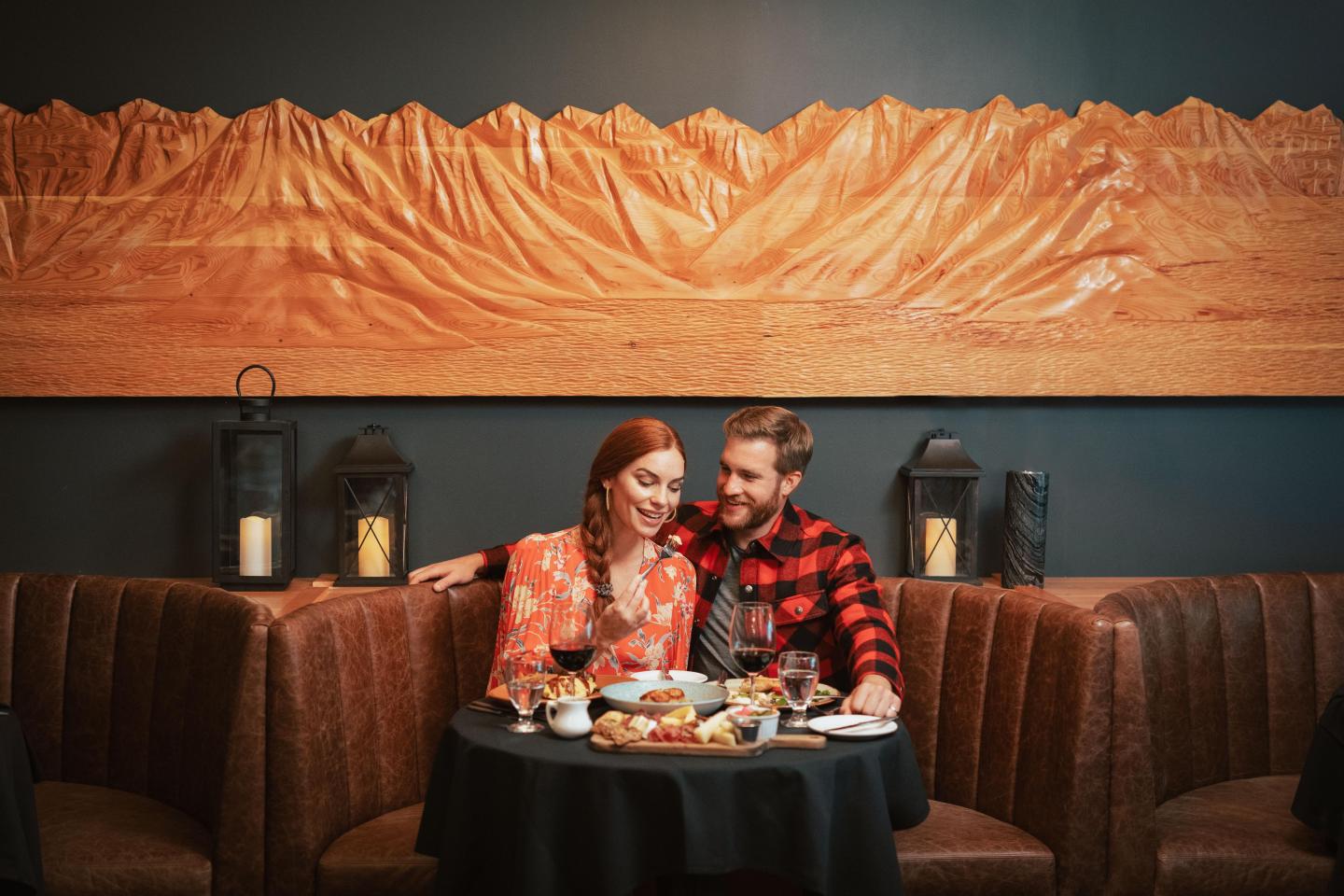 Couple dining at a restaurant, seated in a booth with warm lighting and mountain wall art.