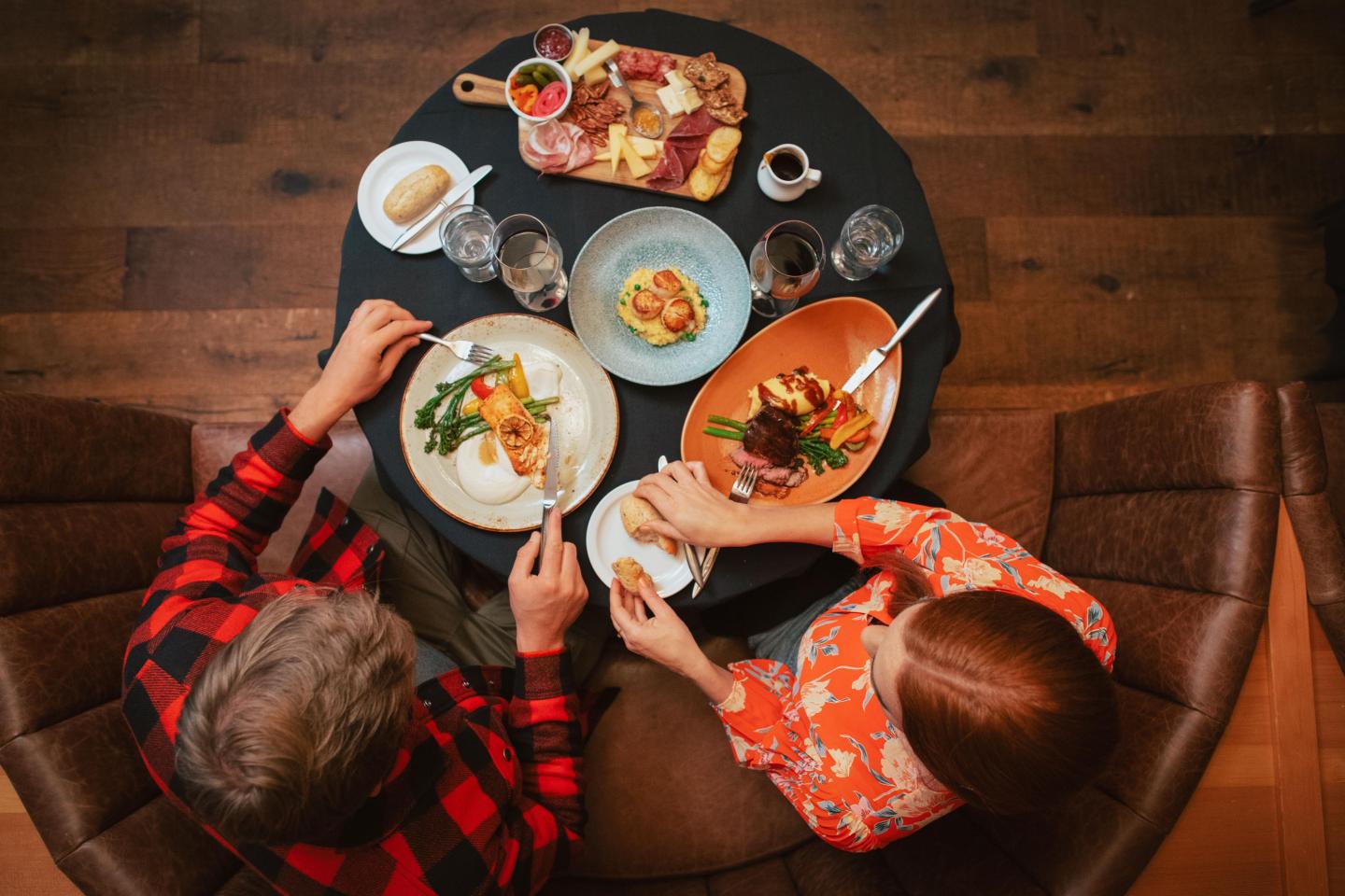 Two people dining at a round table with various dishes, viewed from above.