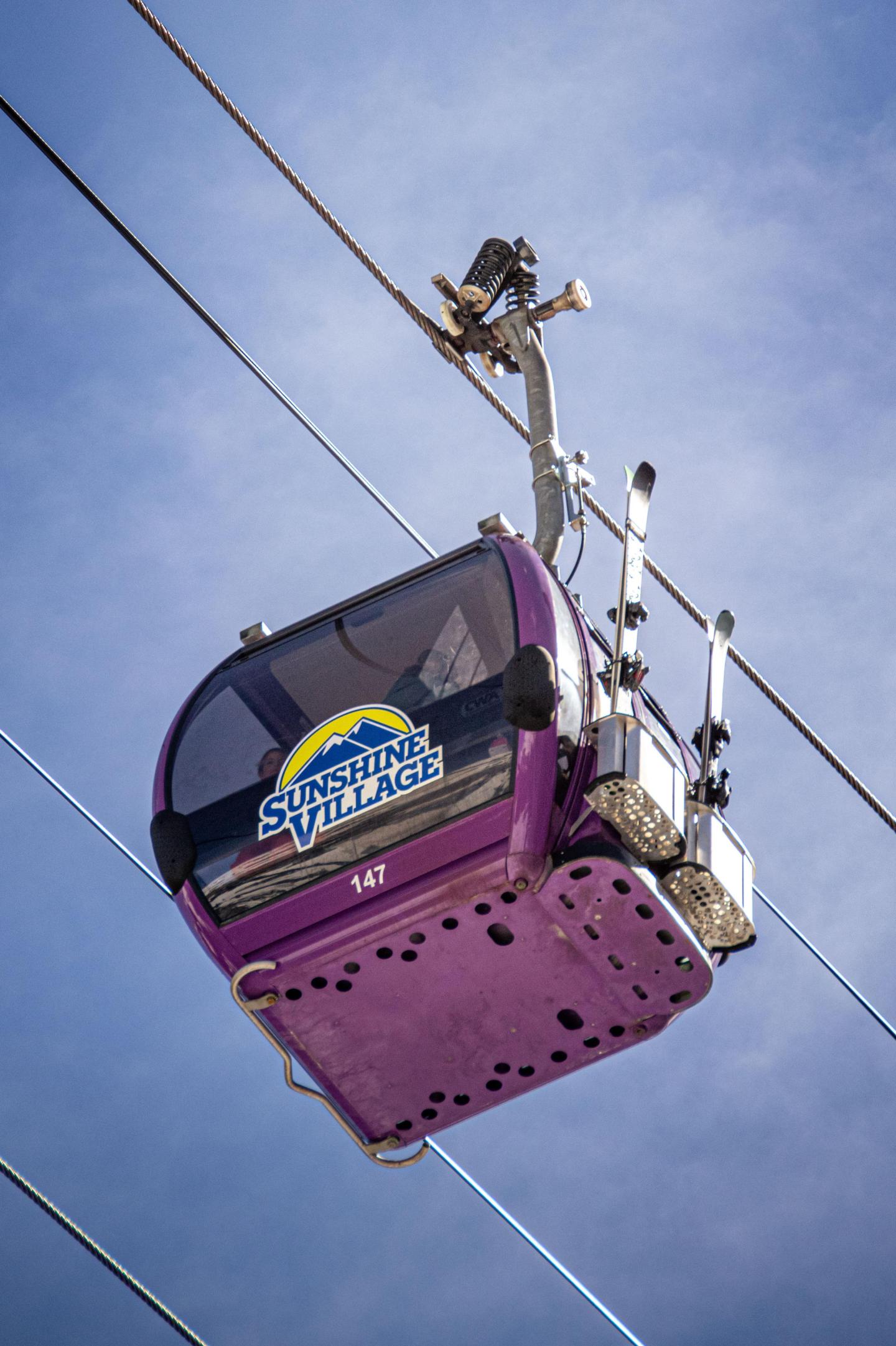Purple ski lift gondola against a clear blue sky.
