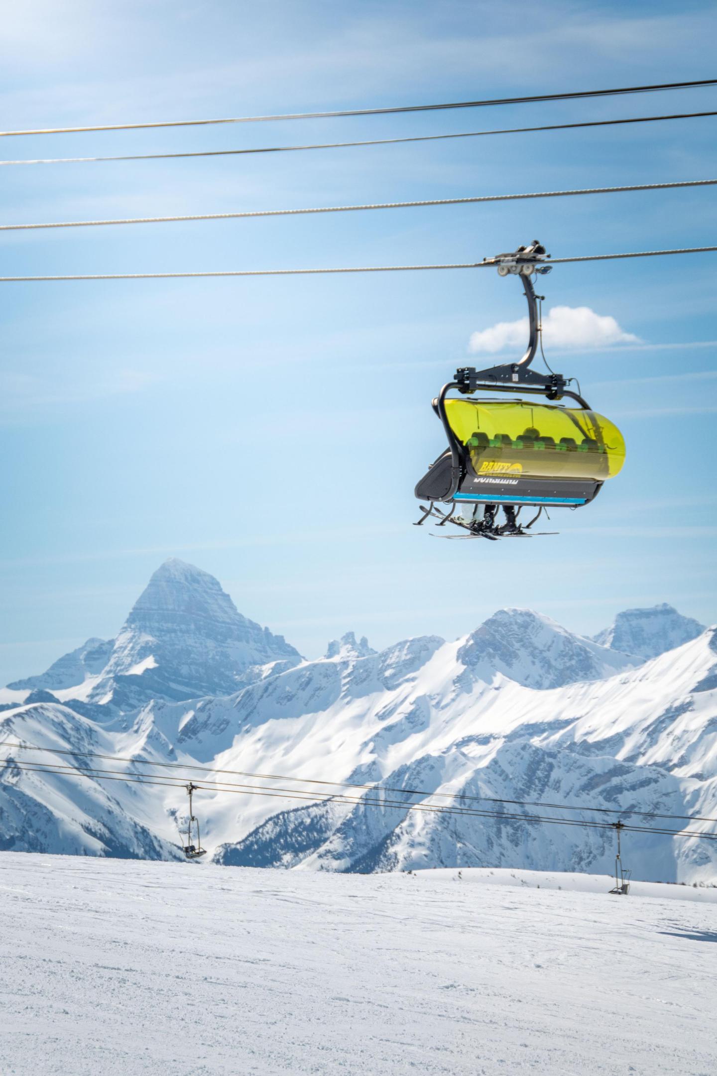 Ski lift against snowy mountain backdrop under clear blue sky.
