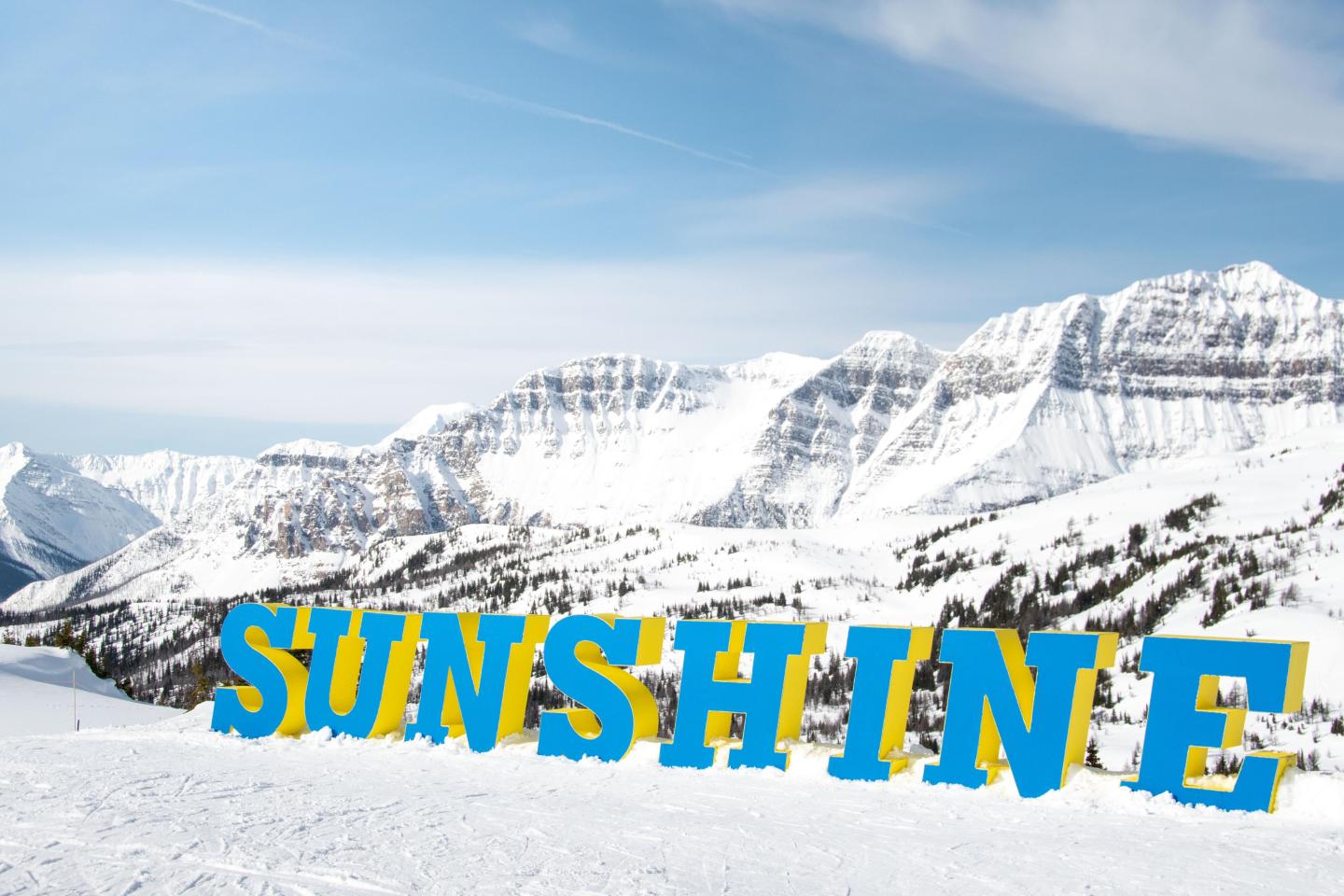 Snowy mountain landscape with blue sky and large "SUNSHINE" letters in foreground.
