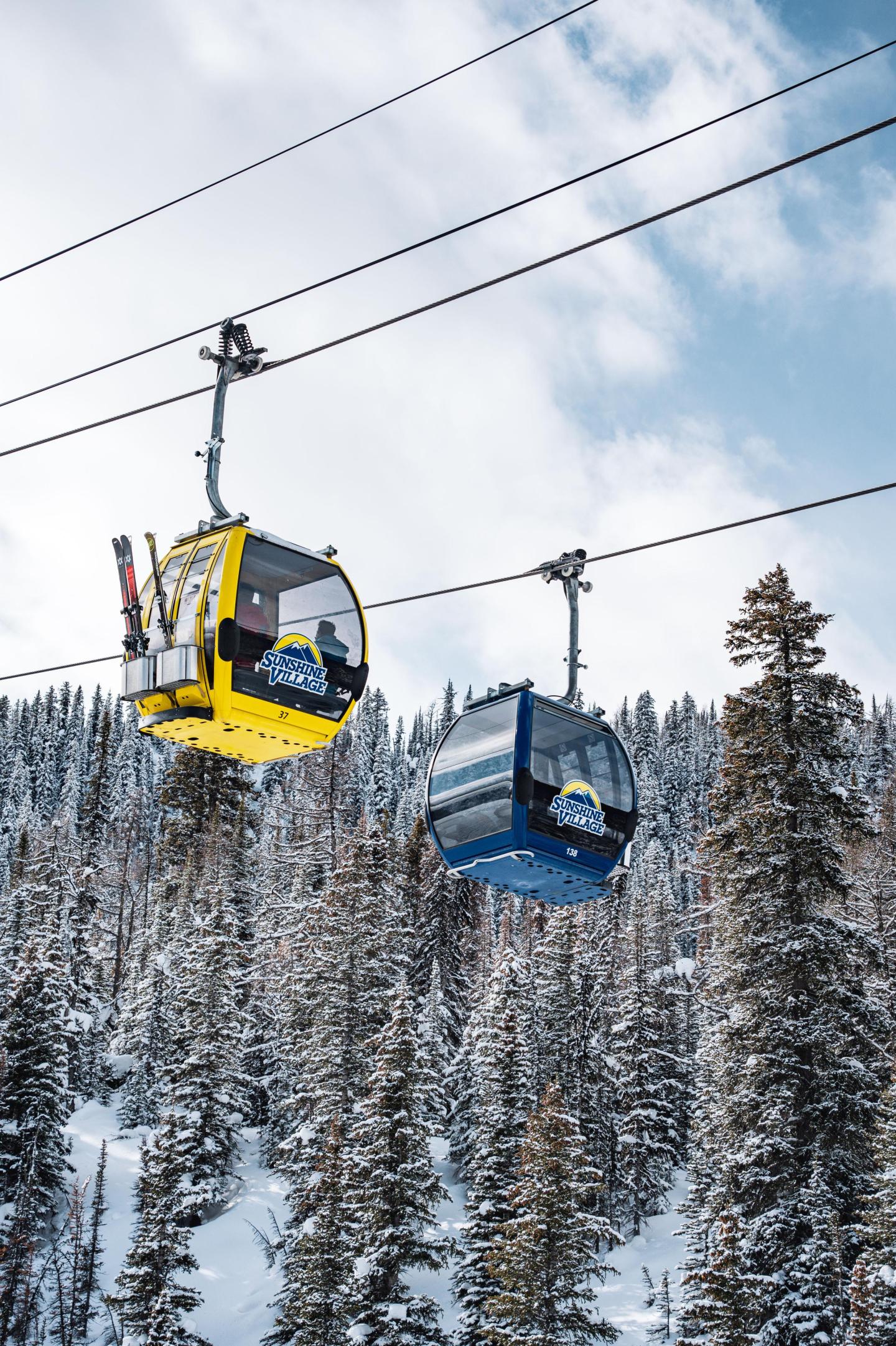 Yellow and blue gondolas in snowy mountain landscape.