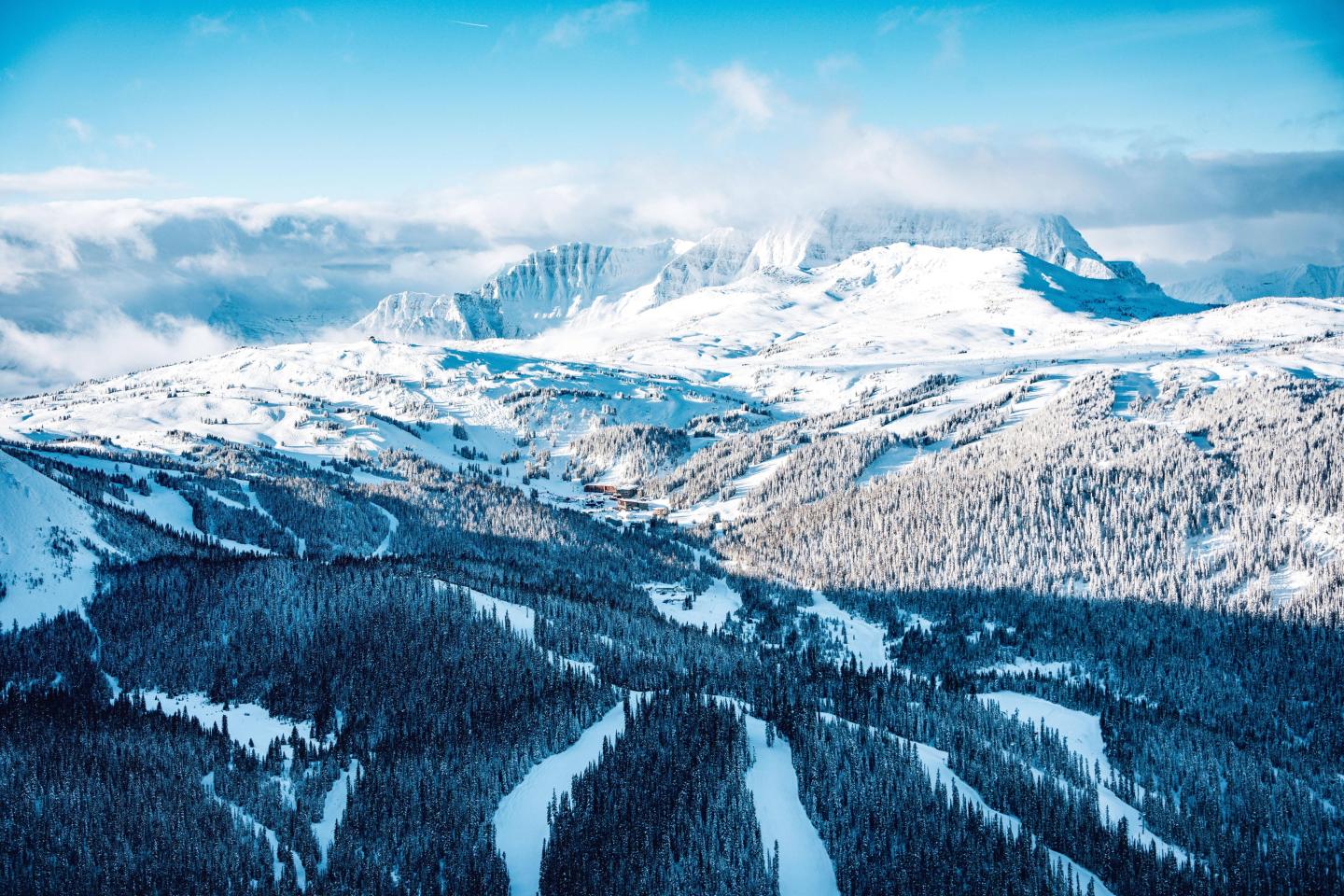 Snow-covered mountains and valleys under a bright blue sky.