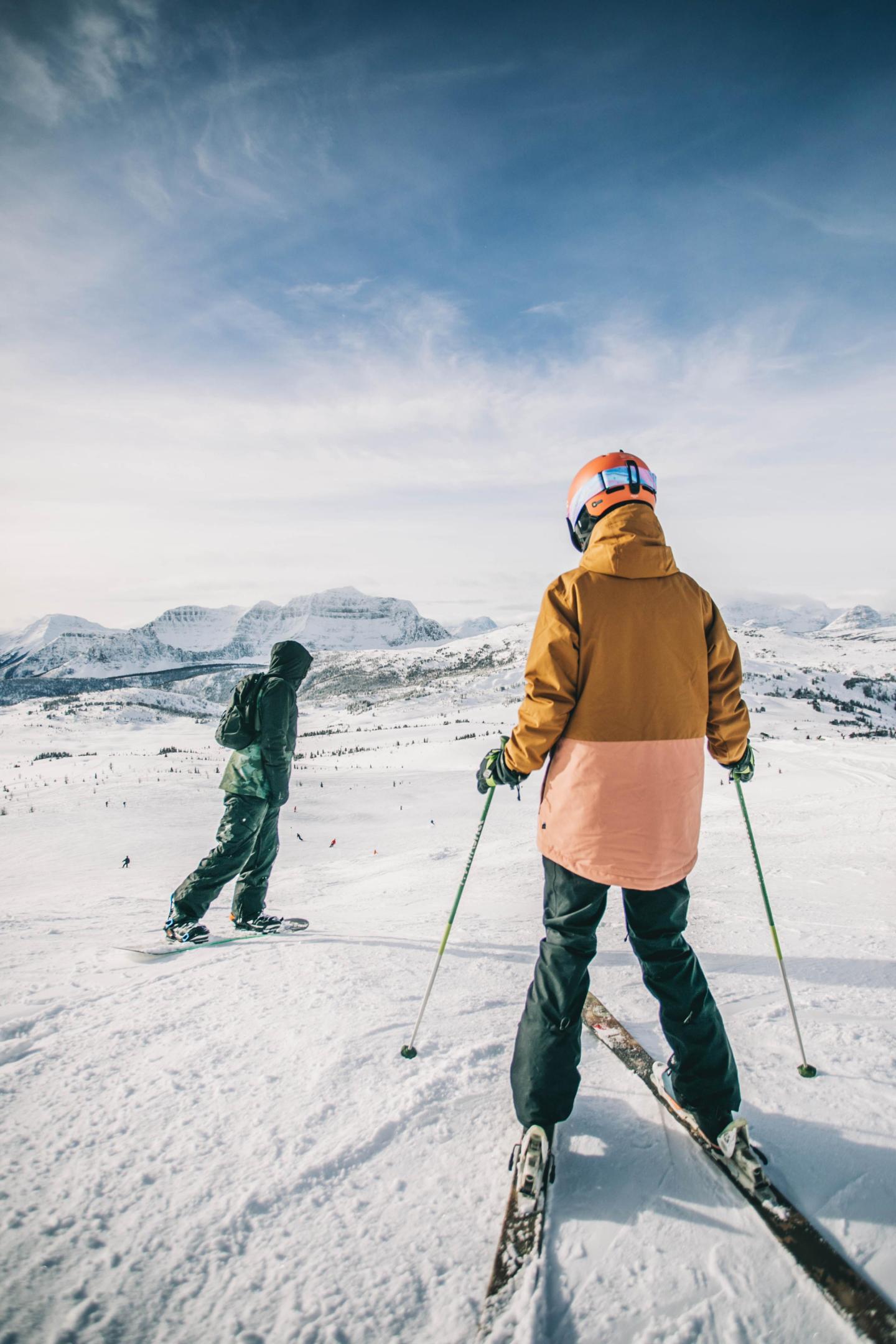 Two skiers on a snowy mountain, cloudy sky above.