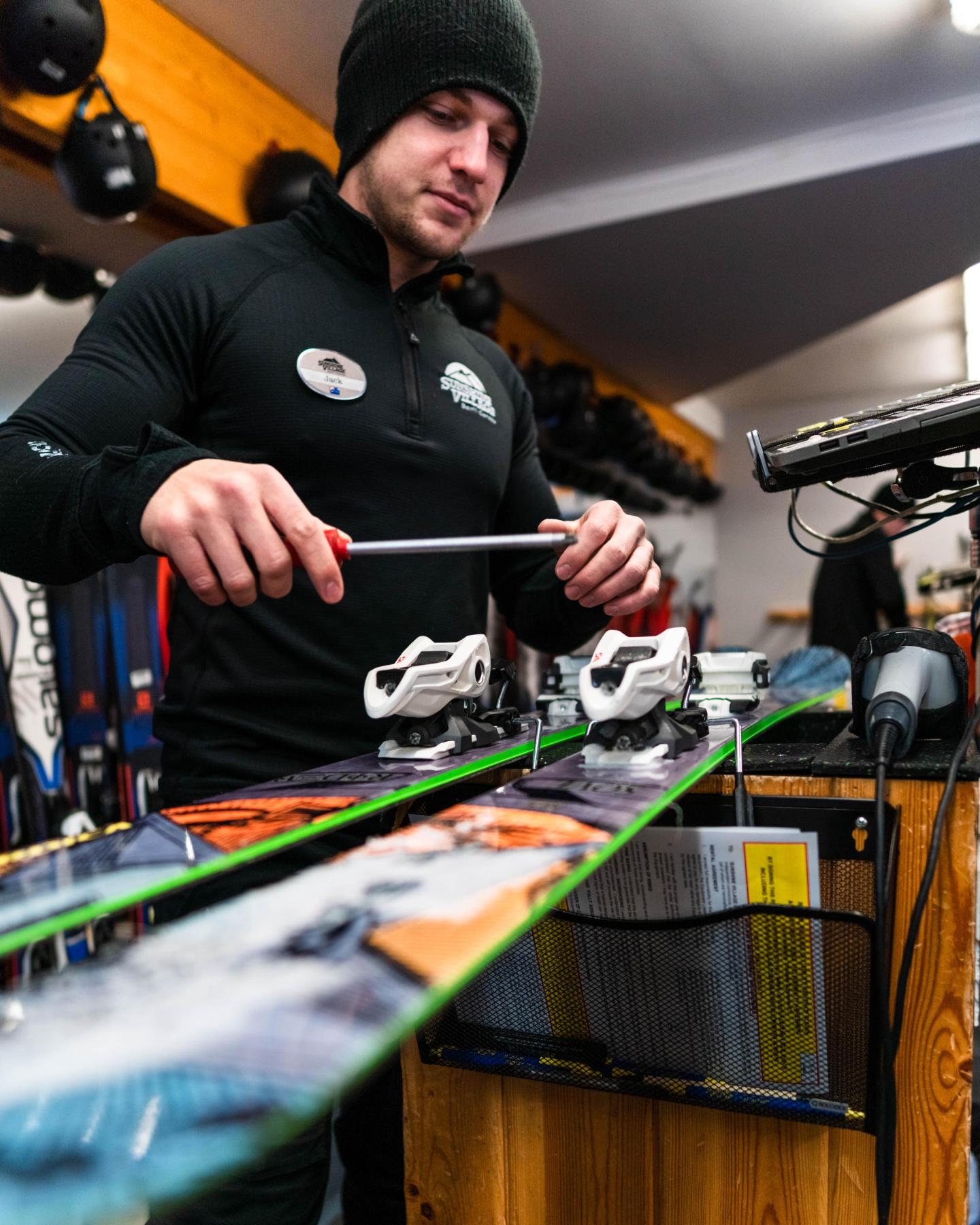 Man adjusting ski bindings in a workshop.