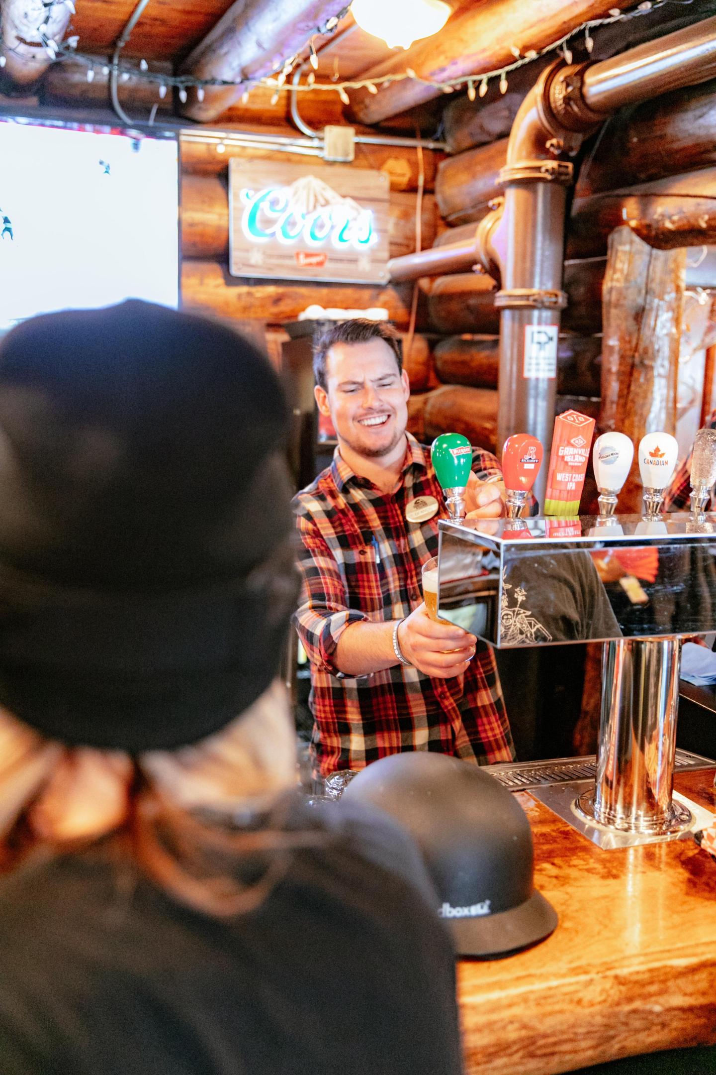Smiling bartender in a rustic bar serving a drink.