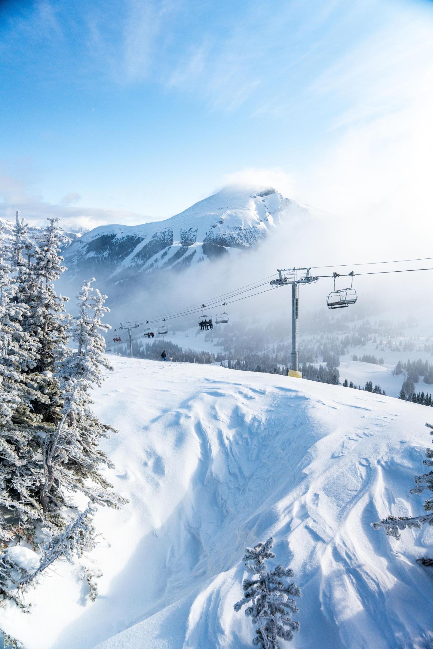 Snowy mountain landscape with ski lift and clear blue sky.