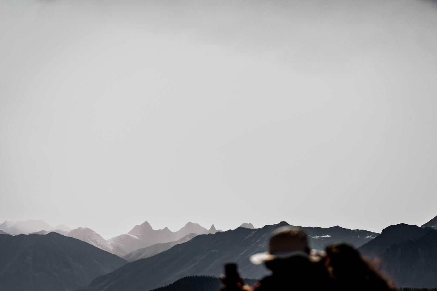 Silhouettes of two people against misty mountain range.