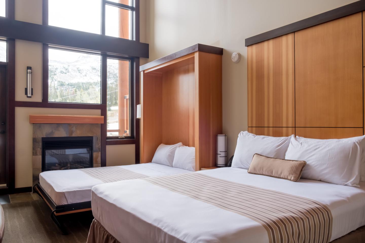 Cozy hotel room with two beds, wooden accents, and a large window.
