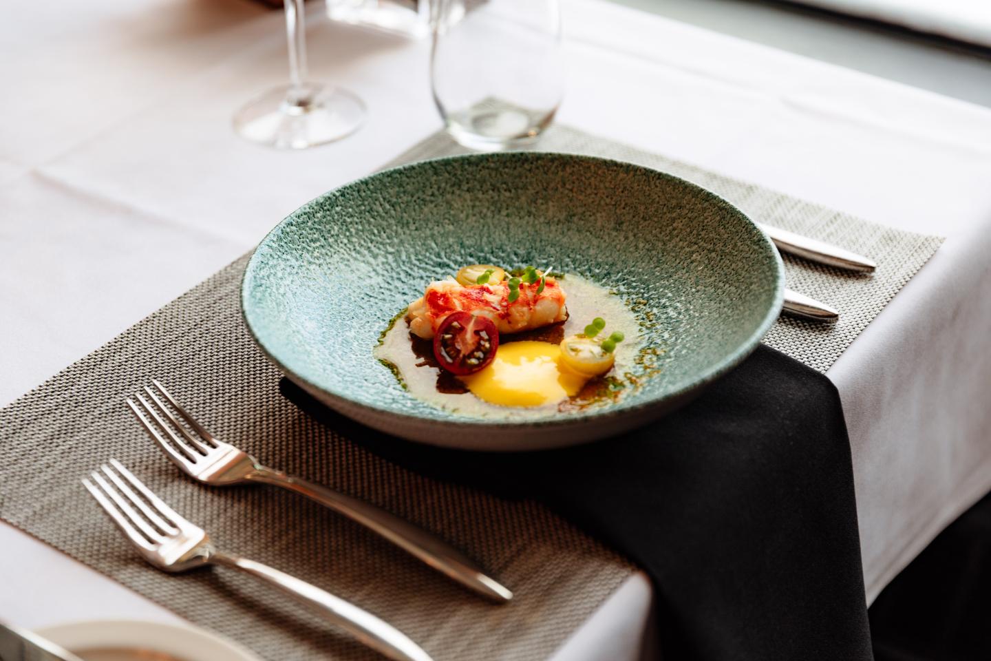 Gourmet plated dish with vegetables and sauce on a restaurant table.