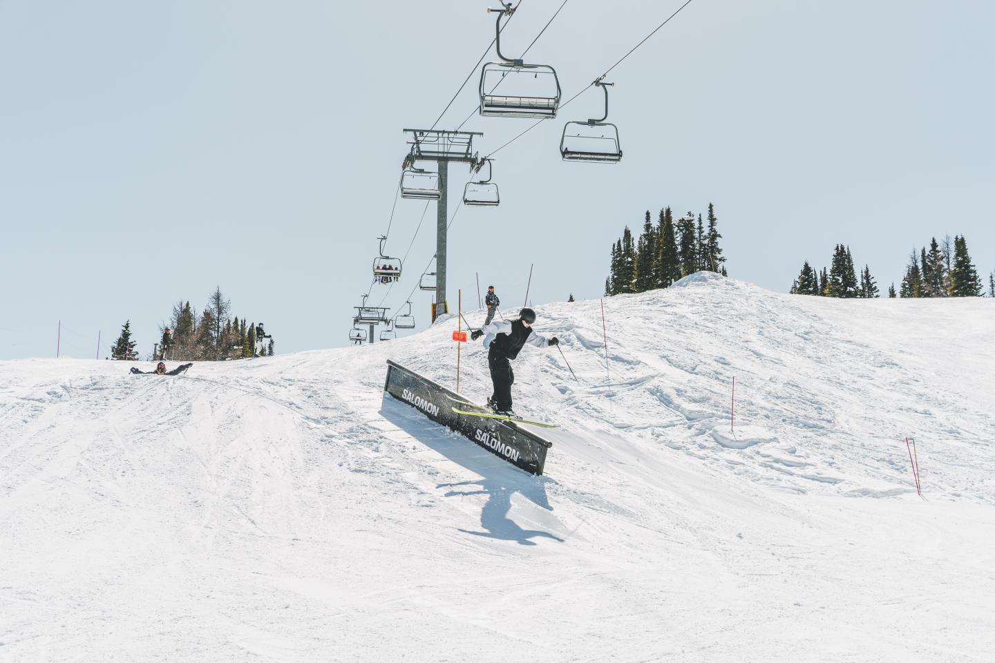 Snowboarder jumping beside a ski lift on a sunny, snowy slope.