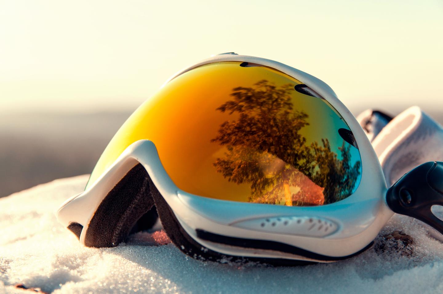 Ski goggles with orange reflective lenses resting on snow.