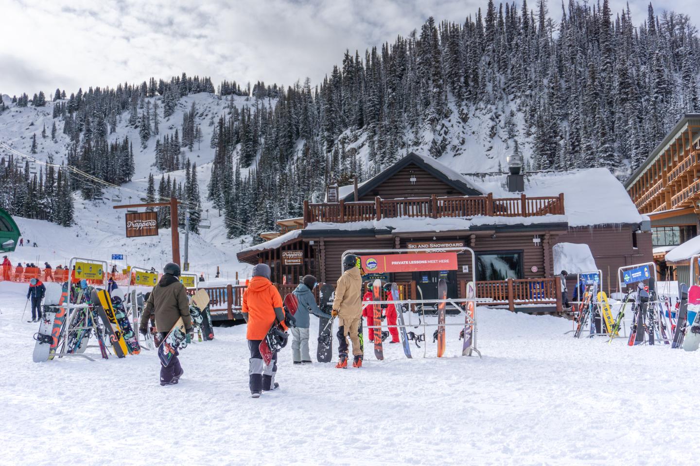 Skiers gather near a lodge in a snowy mountain setting.