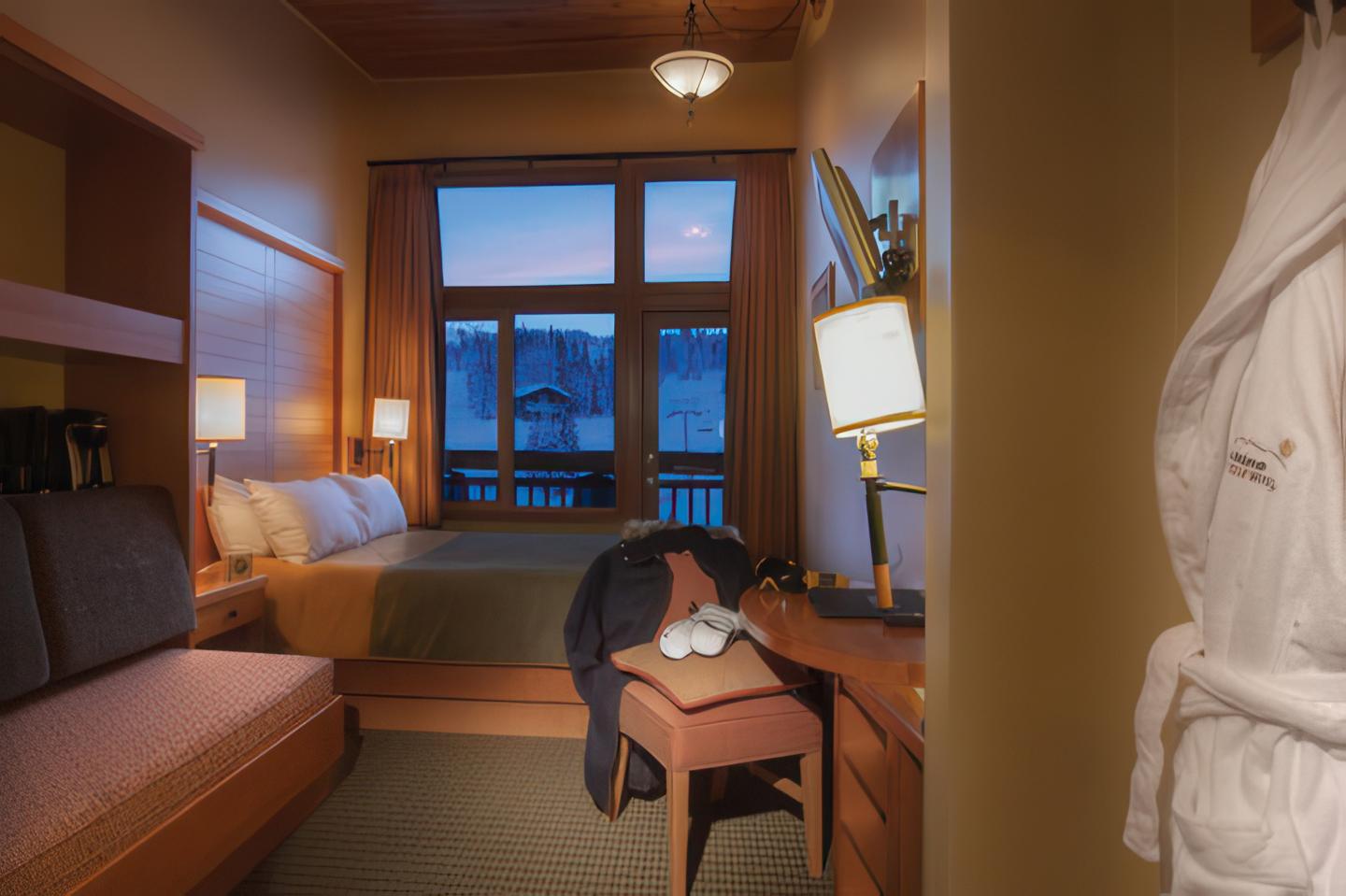 Cozy hotel room with sofa, desk, and a white robe hanging in the foreground.