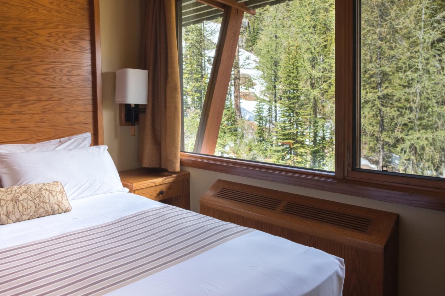 Cozy bedroom with large window view of forest.