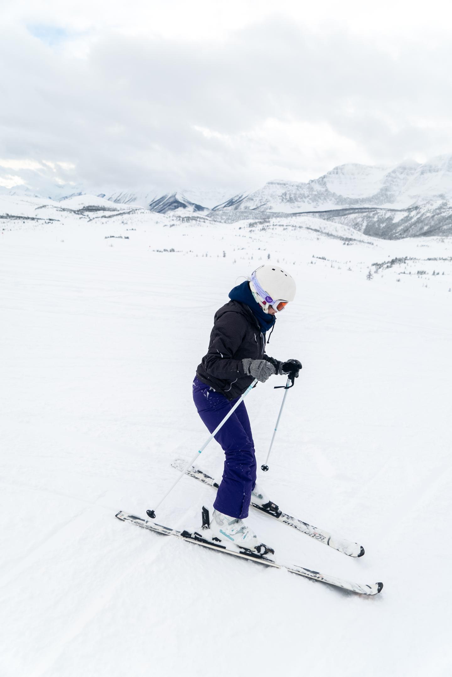 Person skiing downhill on a snowy mountain slope.