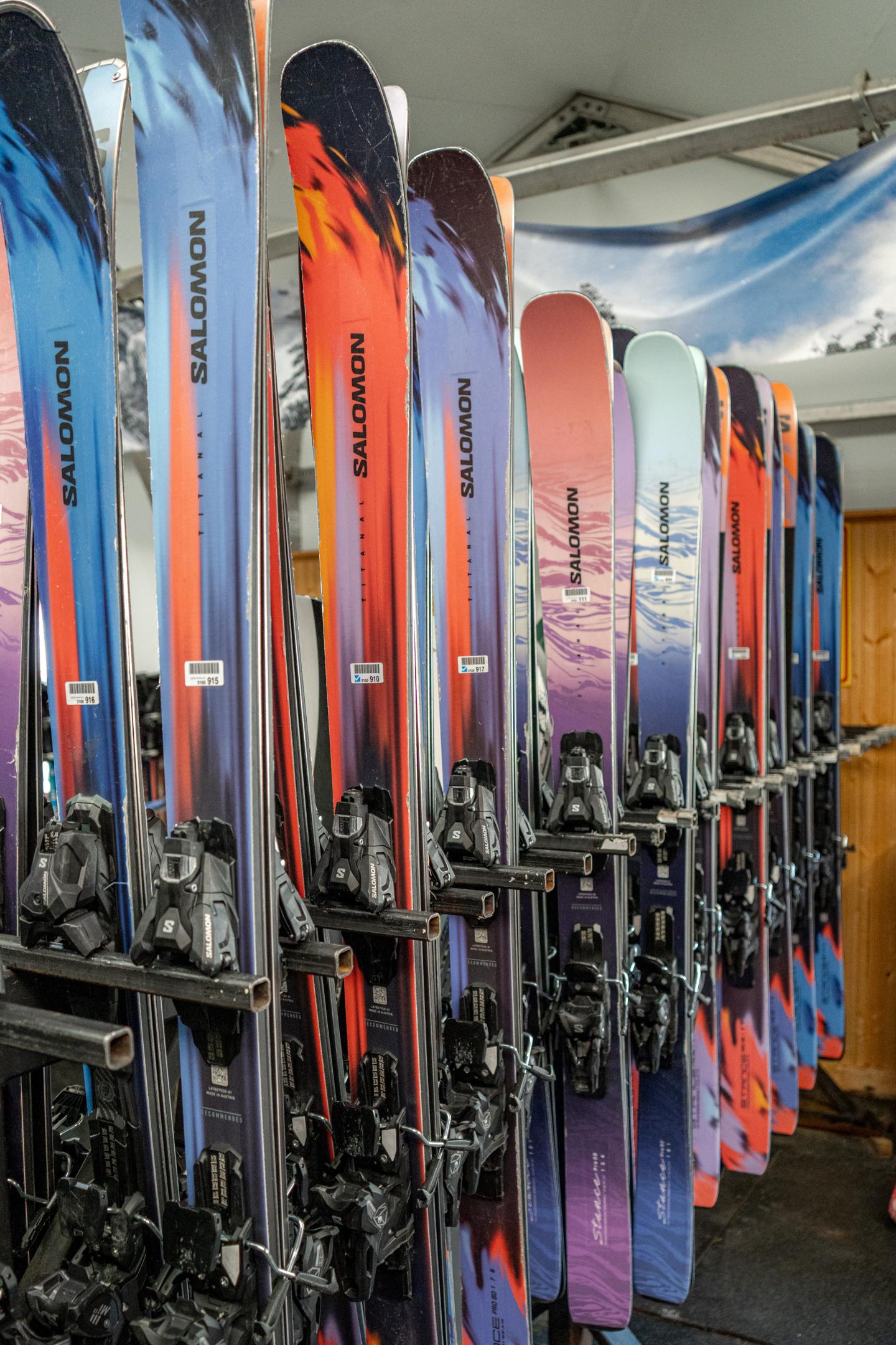 Colorful skis arranged vertically in a storage rack.