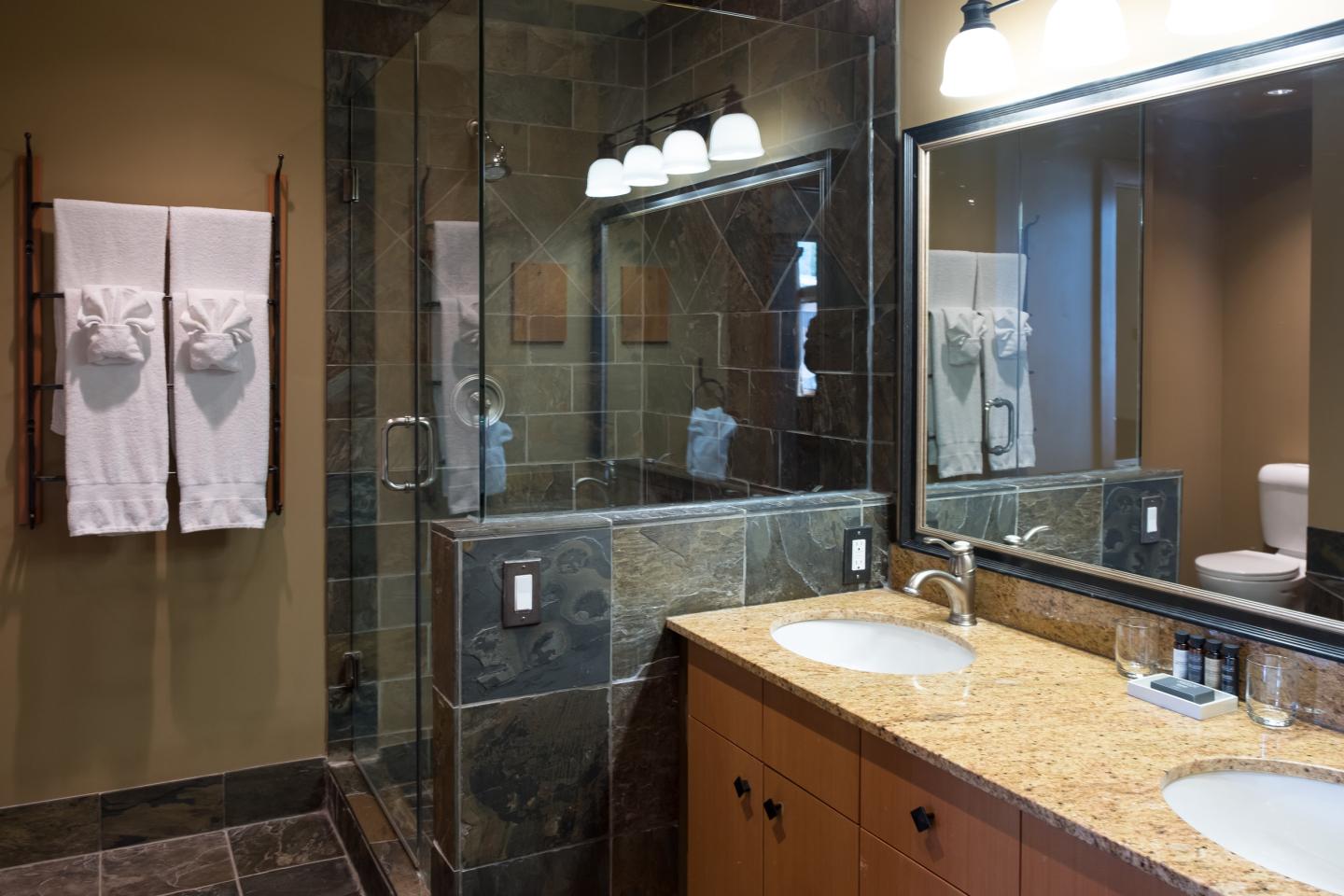 Modern bathroom with wood vanity, large mirror, and glass walk-in shower.