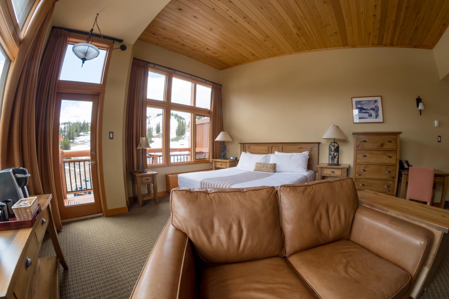 Cozy cabin living room with leather armchair, fireplace, and large windows.