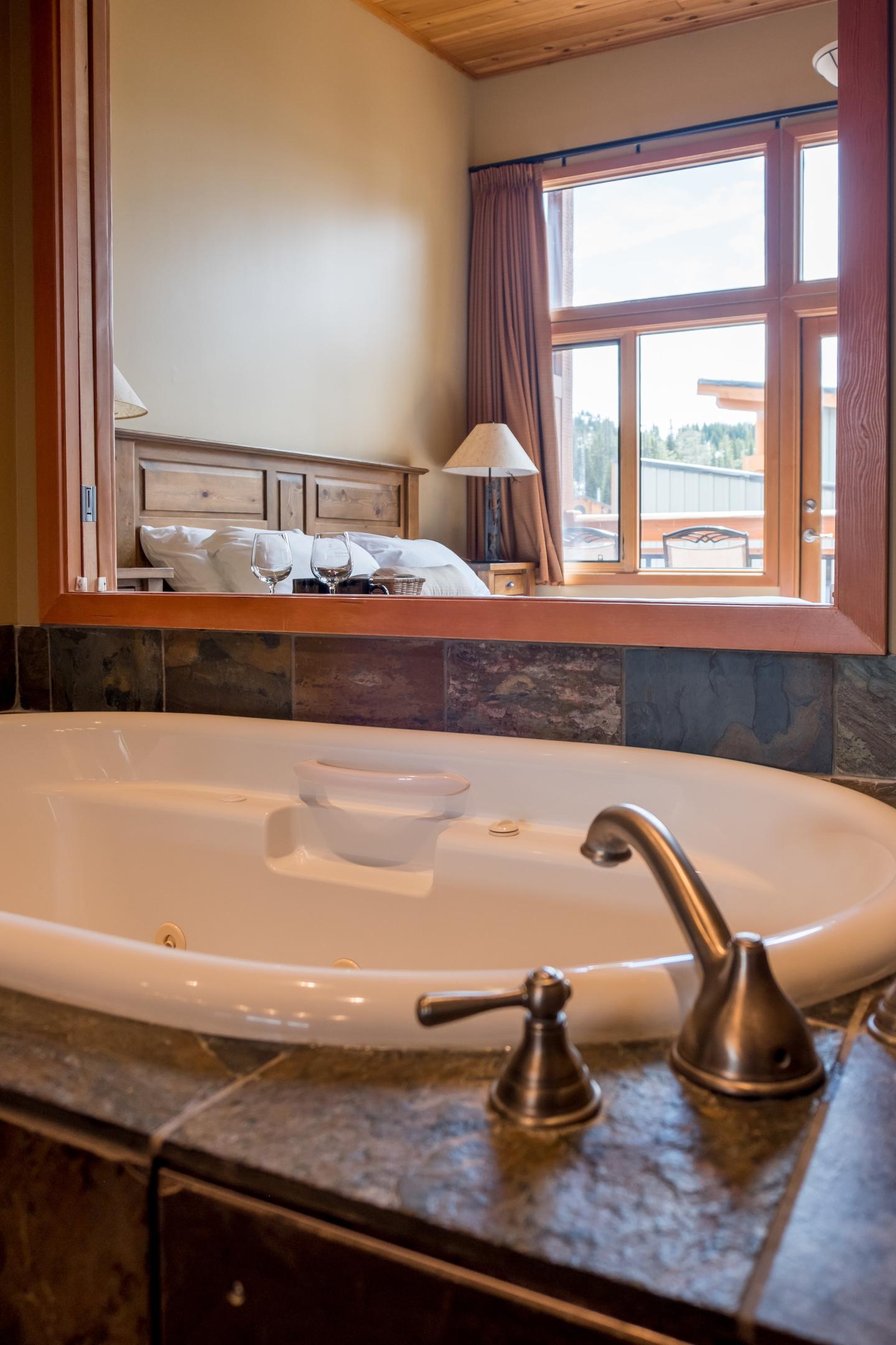 Freestanding bathtub with brass faucet in a warm, wood-paneled bathroom.