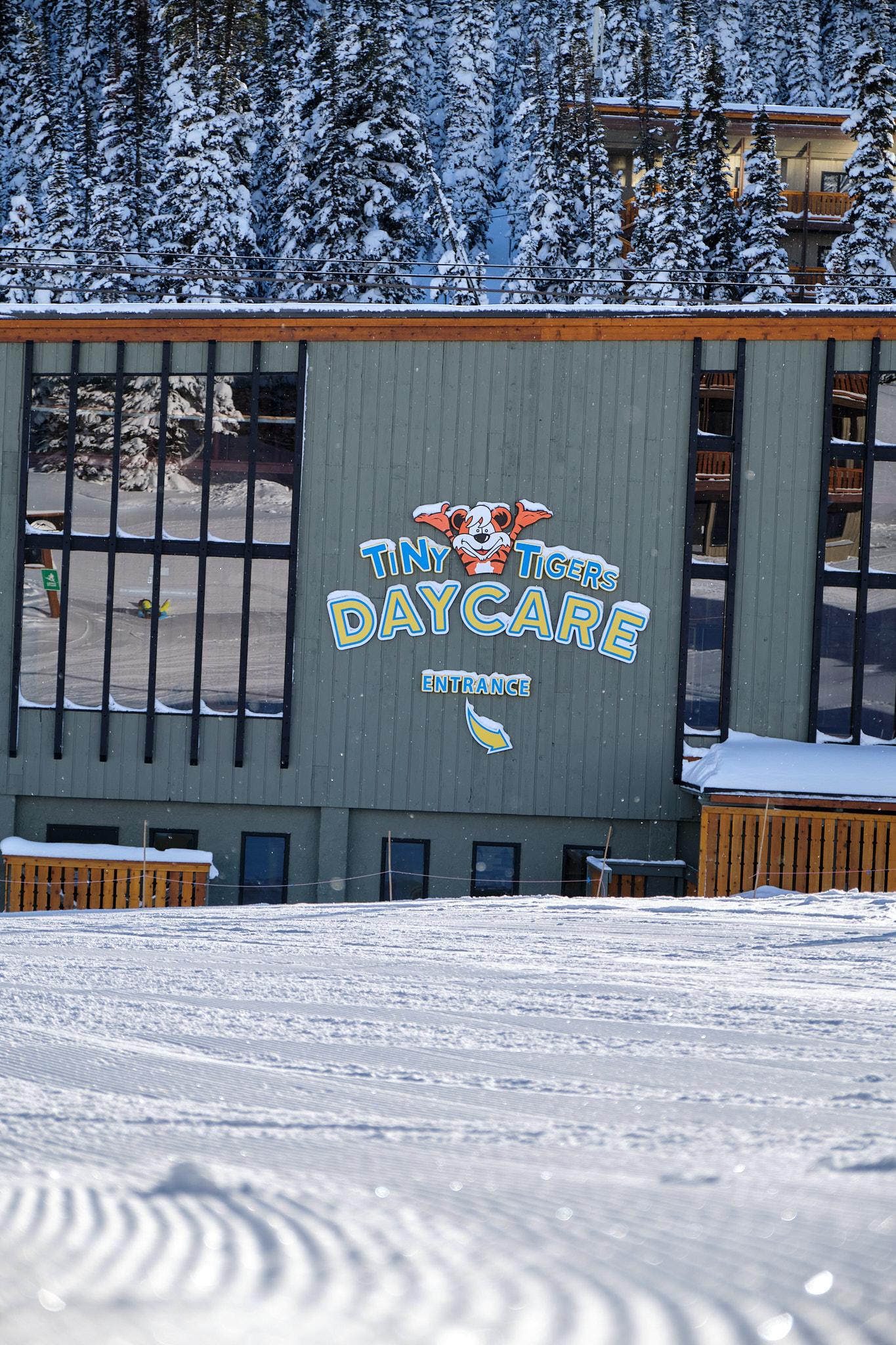 Snow-covered building with daycare sign, snowy trees in background.