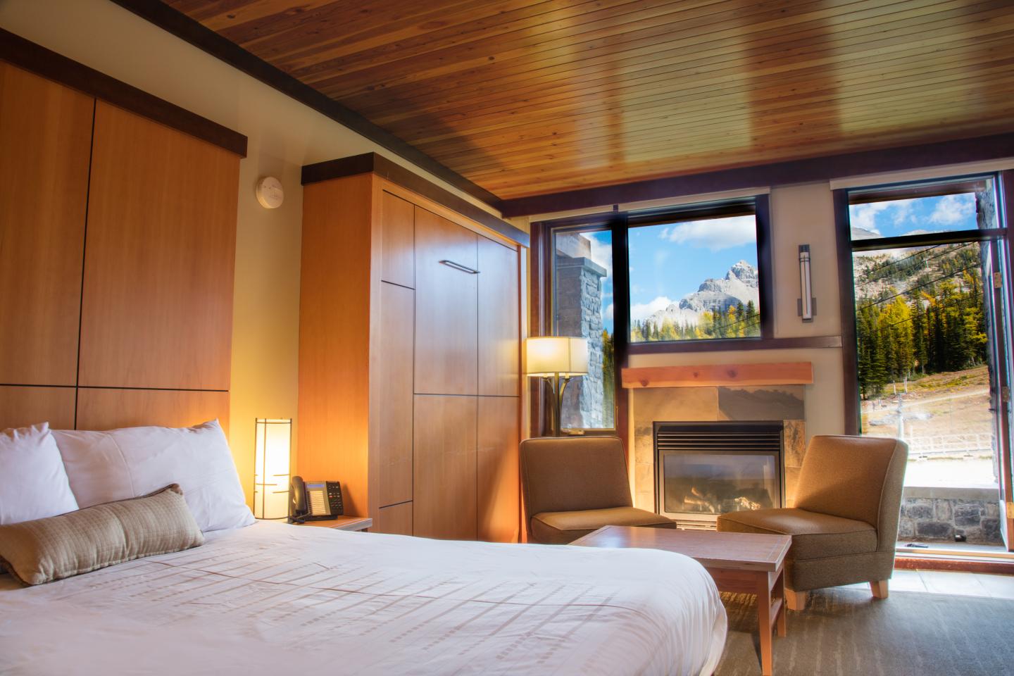 Cozy bedroom with a large bed, fireplace, and mountain view through the window.
