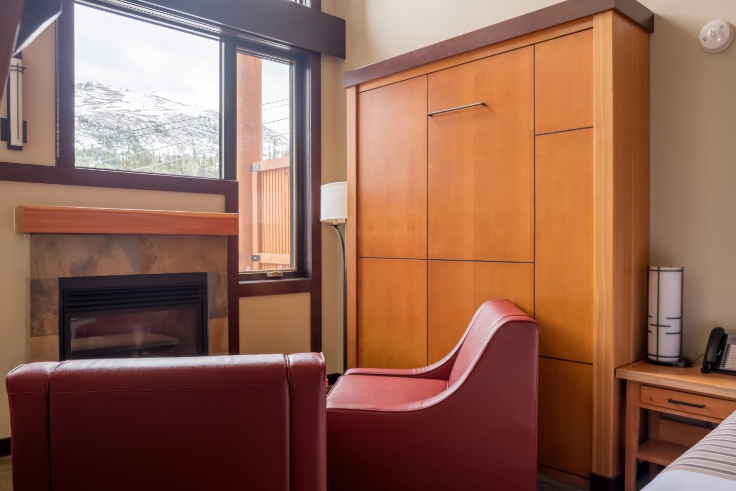 Cozy office with red chairs, fireplace, and wooden cabinet.