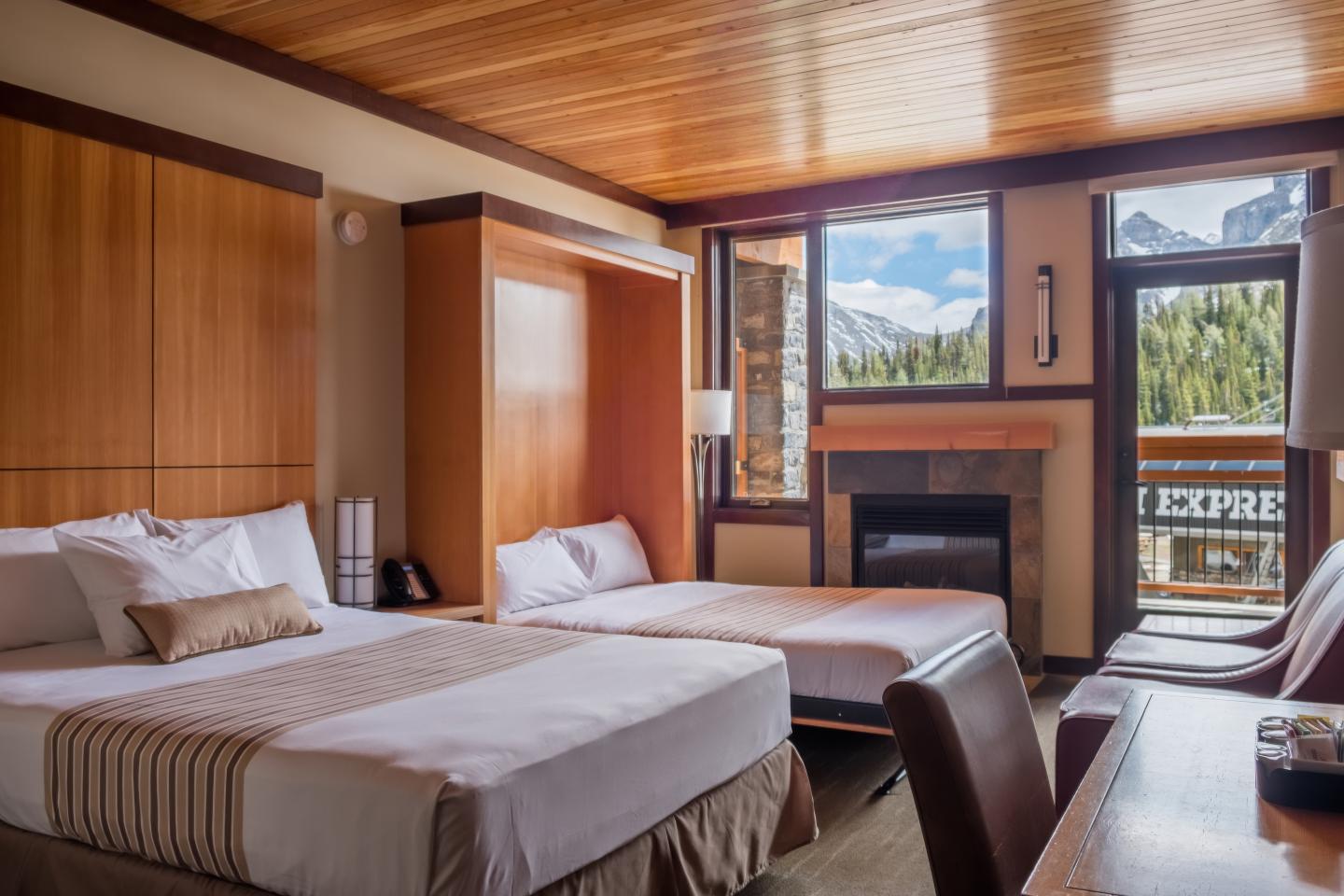Cozy hotel room with two beds, wooden decor, and a mountain view.