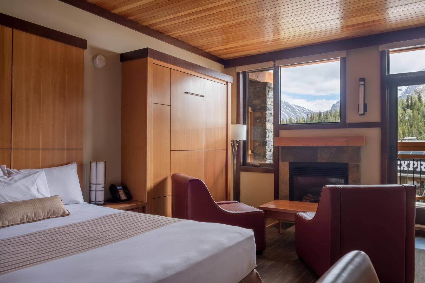 Cozy hotel room with a king bed, fireplace, and mountain view.