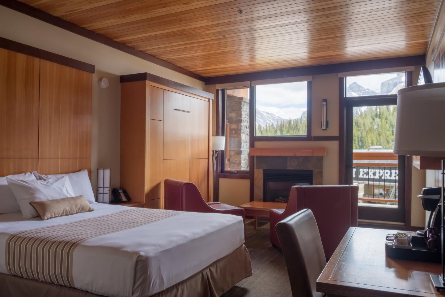 Cozy hotel room with a bed, seating area, and mountain view.