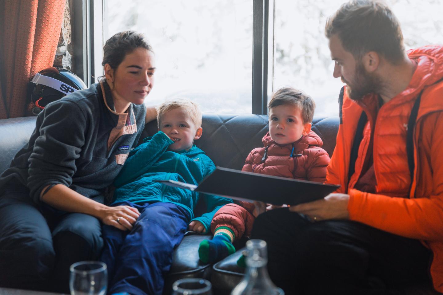 Family sitting together on a train, children between two adults.