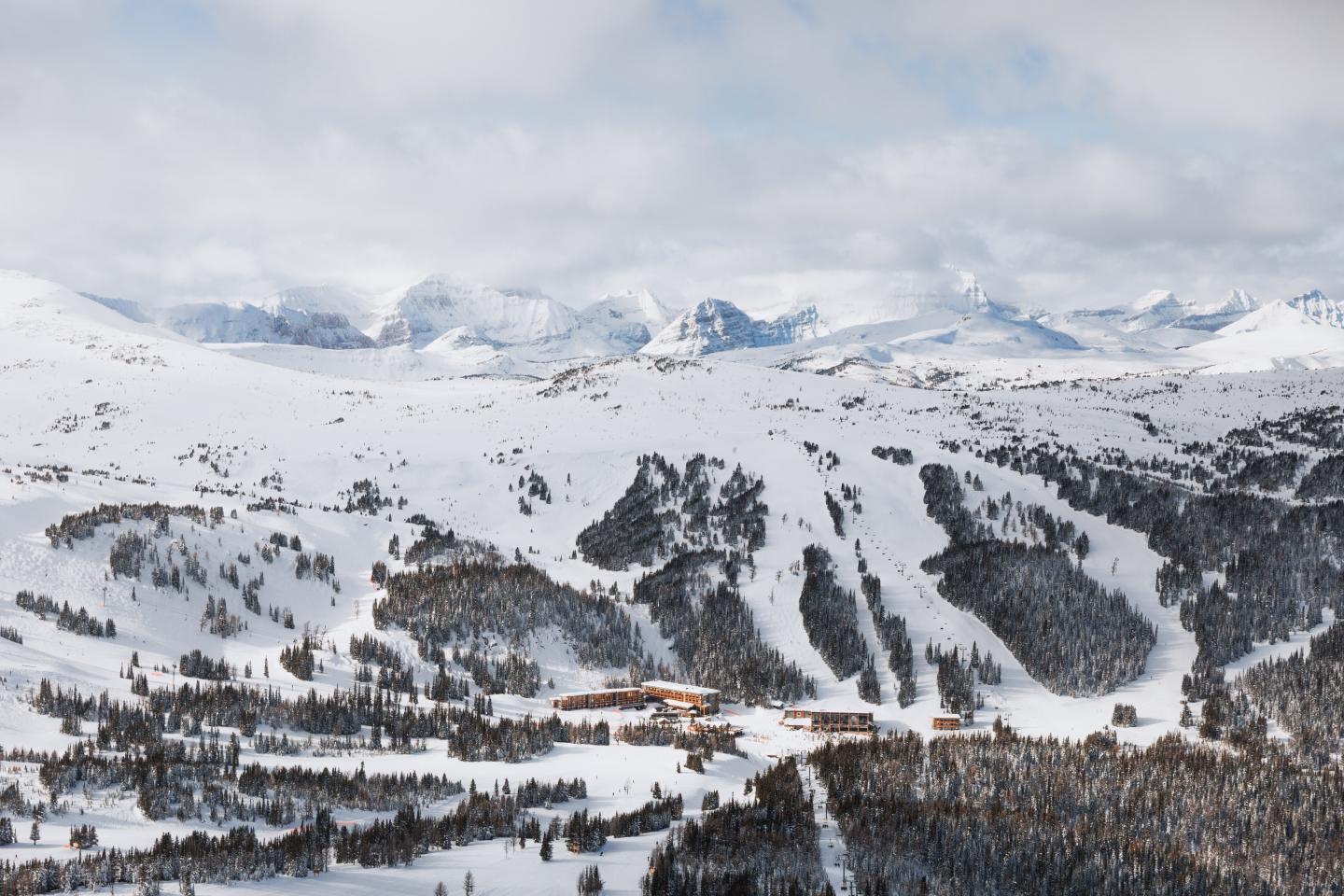 Snow-covered mountain resort with ski slopes and scattered evergreen trees