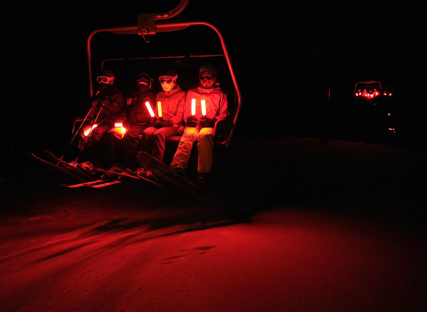 Two people sit in a red-lit off-road vehicle at night.