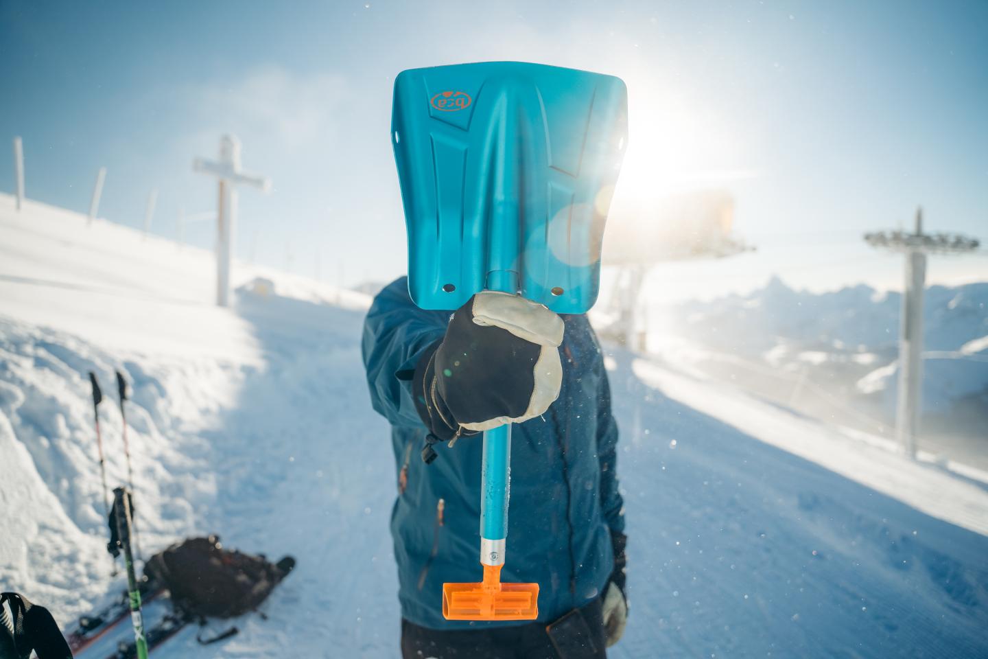 Person in blue winter gear holds a snow-covered boot beside a snowy road.