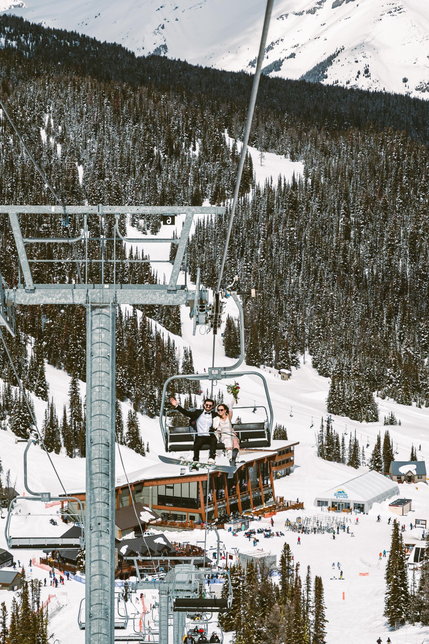 Snowy mountain ski lift ascending above a lodge and forested slope