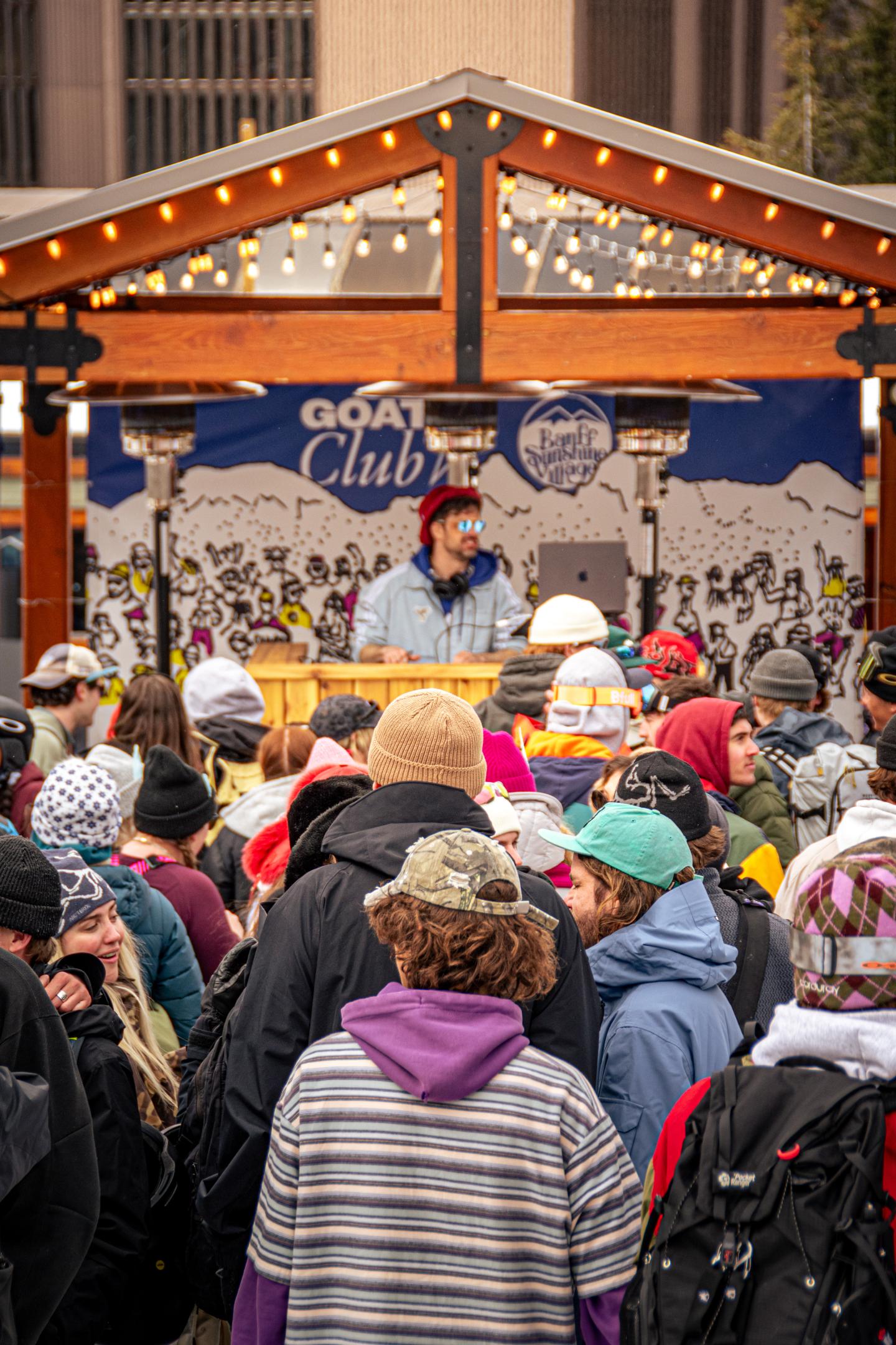 Crowd seated before a decorated outdoor stage during a community event.