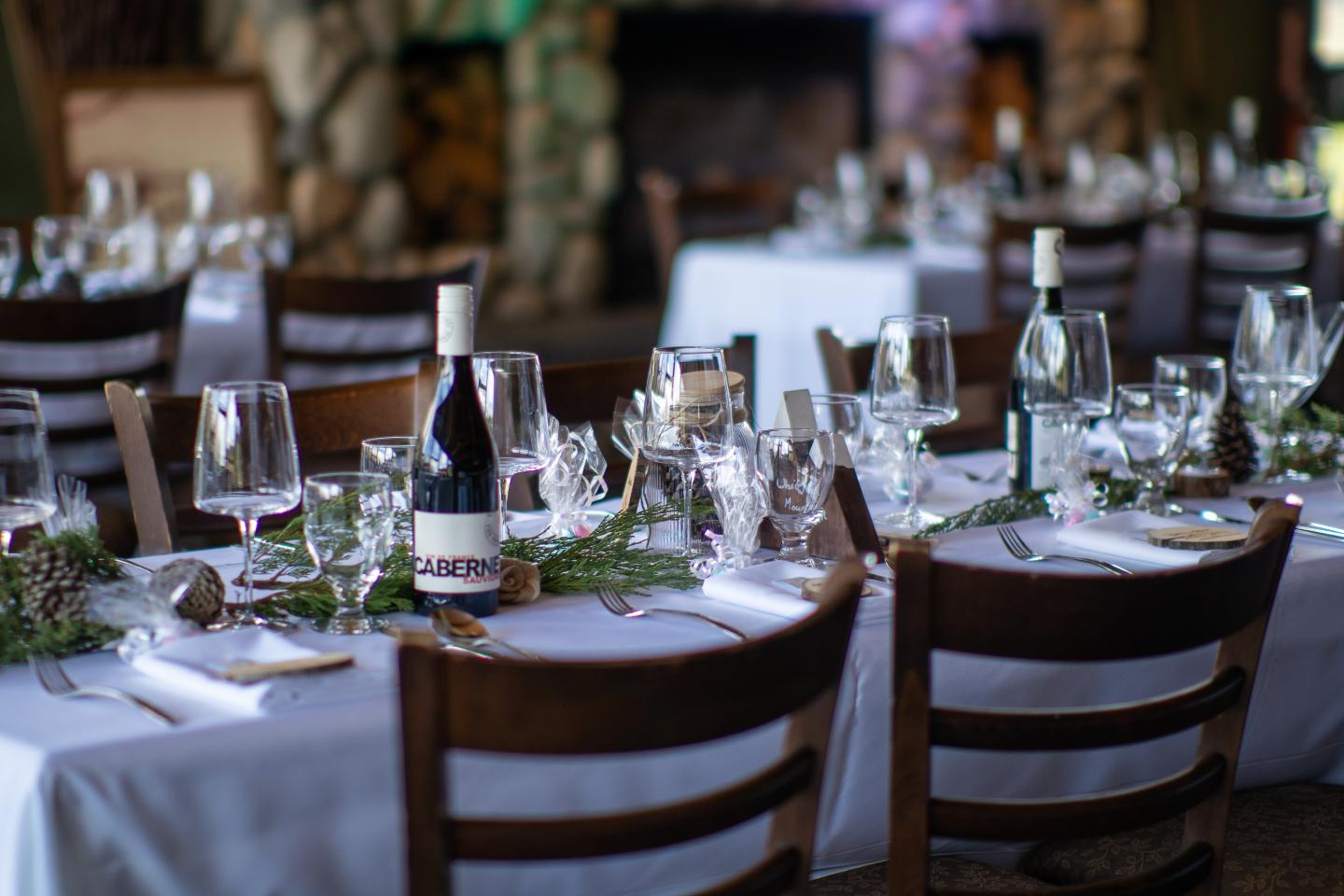 Elegantly set banquet tables with wine glasses and wooden chairs in a restaurant.