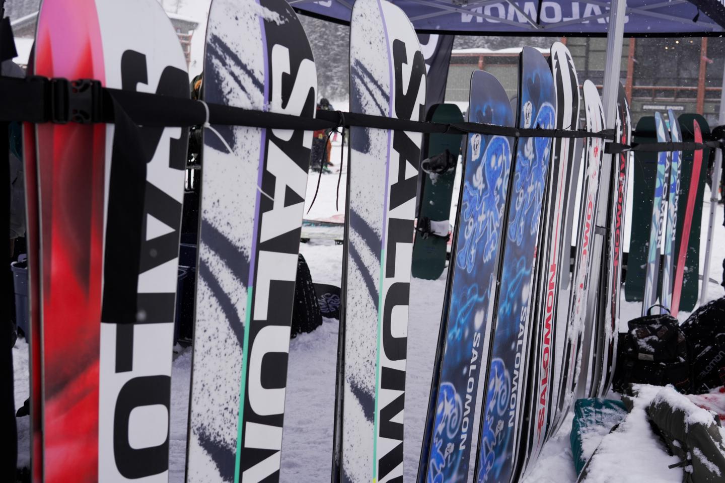 Row of skis and snowboards displayed on a rack outside a shop.