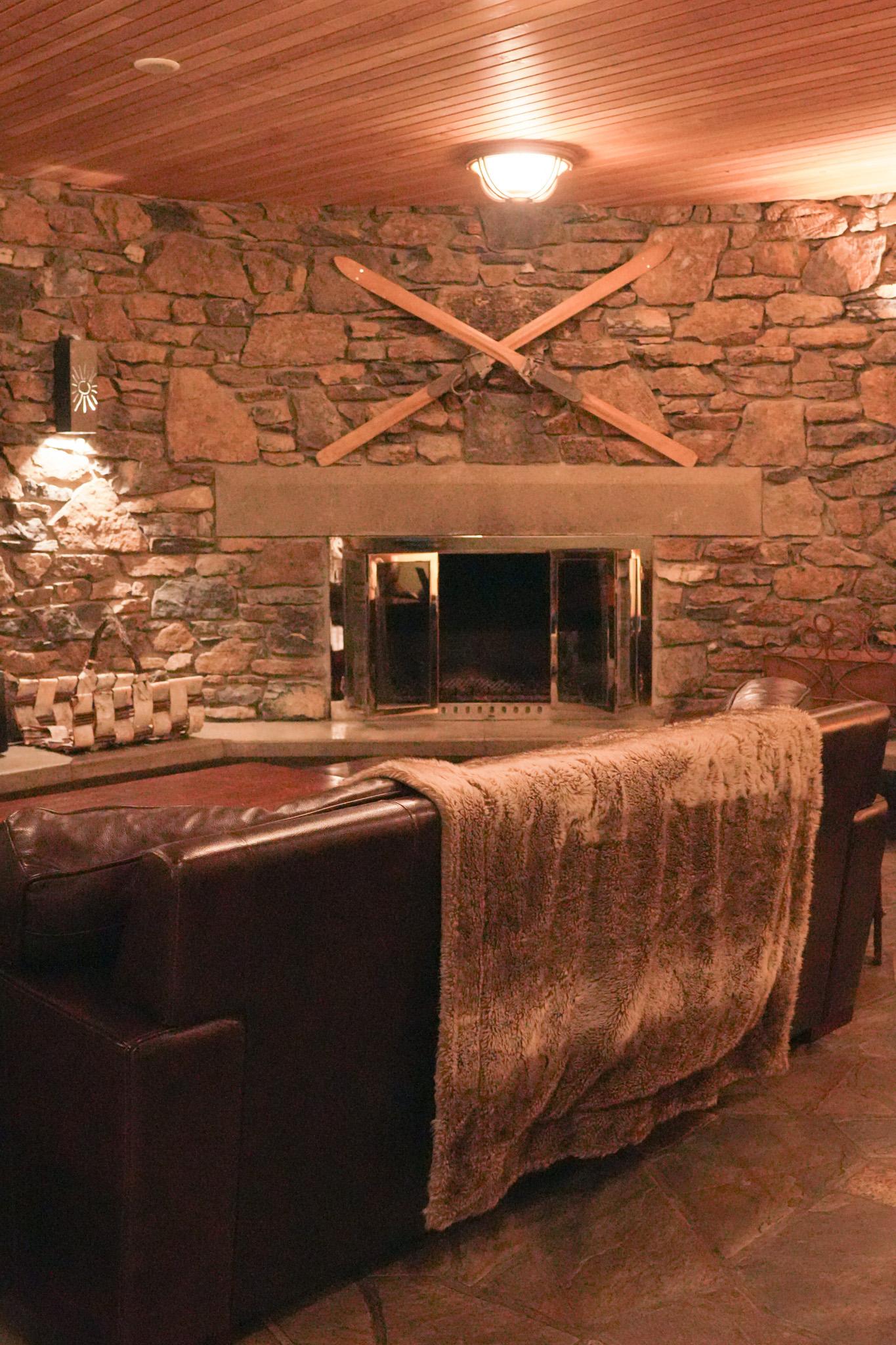 Cozy rustic living room with stone fireplace, crossed oars, and leather sofa.
