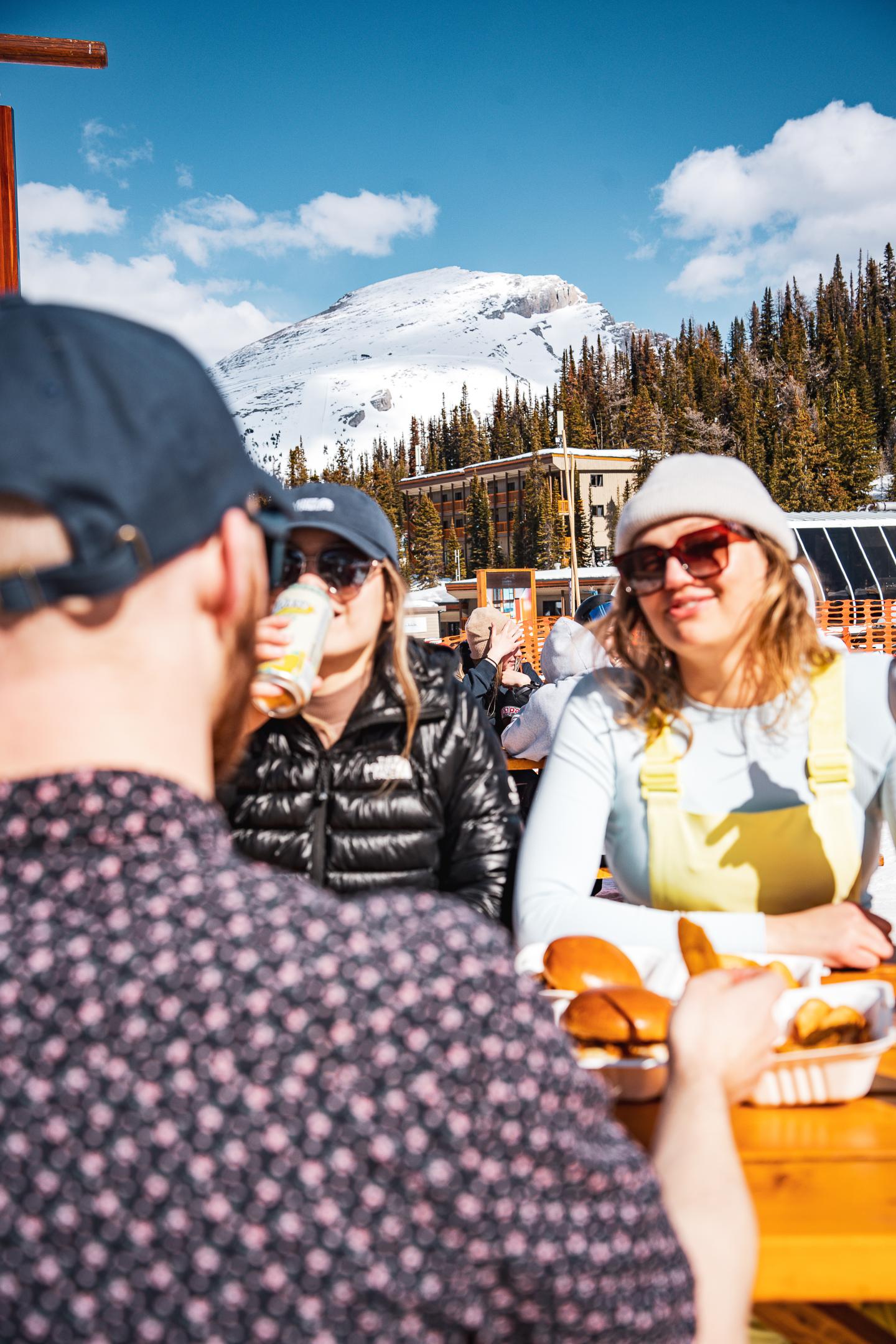 Friends dining outdoors at a snowy mountain ski resort.