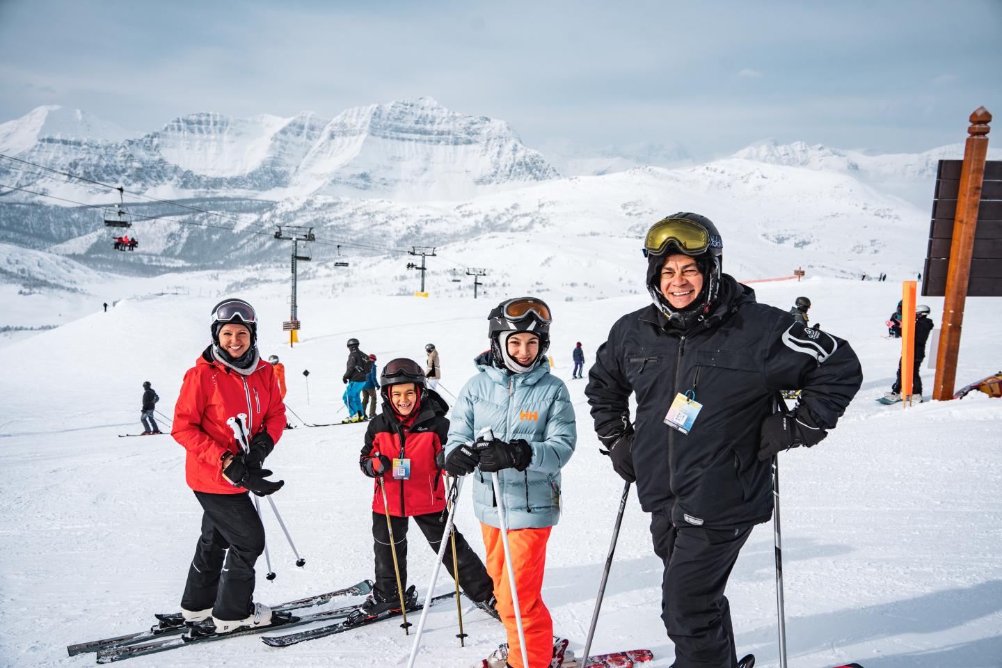 Five skiers in colorful gear pose on a snowy mountain slope.