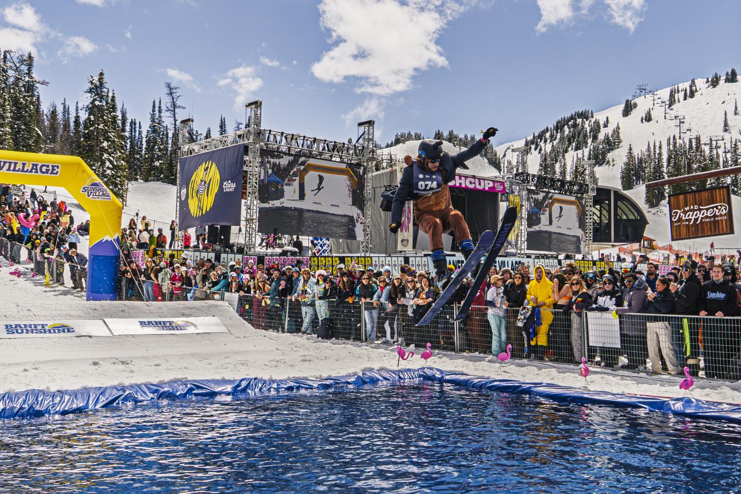 Freestyle skier launches above a pool at a snowy mountain event.