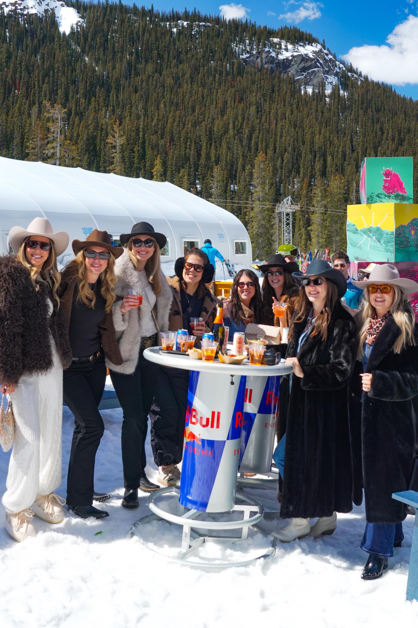Group gathered around a Red Bull table at a snowy mountain event.