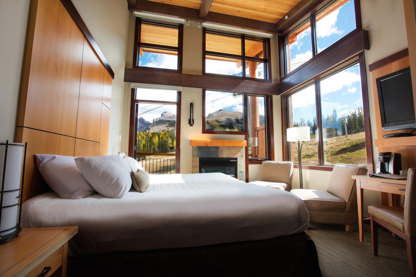 Sunlit modern bedroom with low bed, large windows, and mountain views