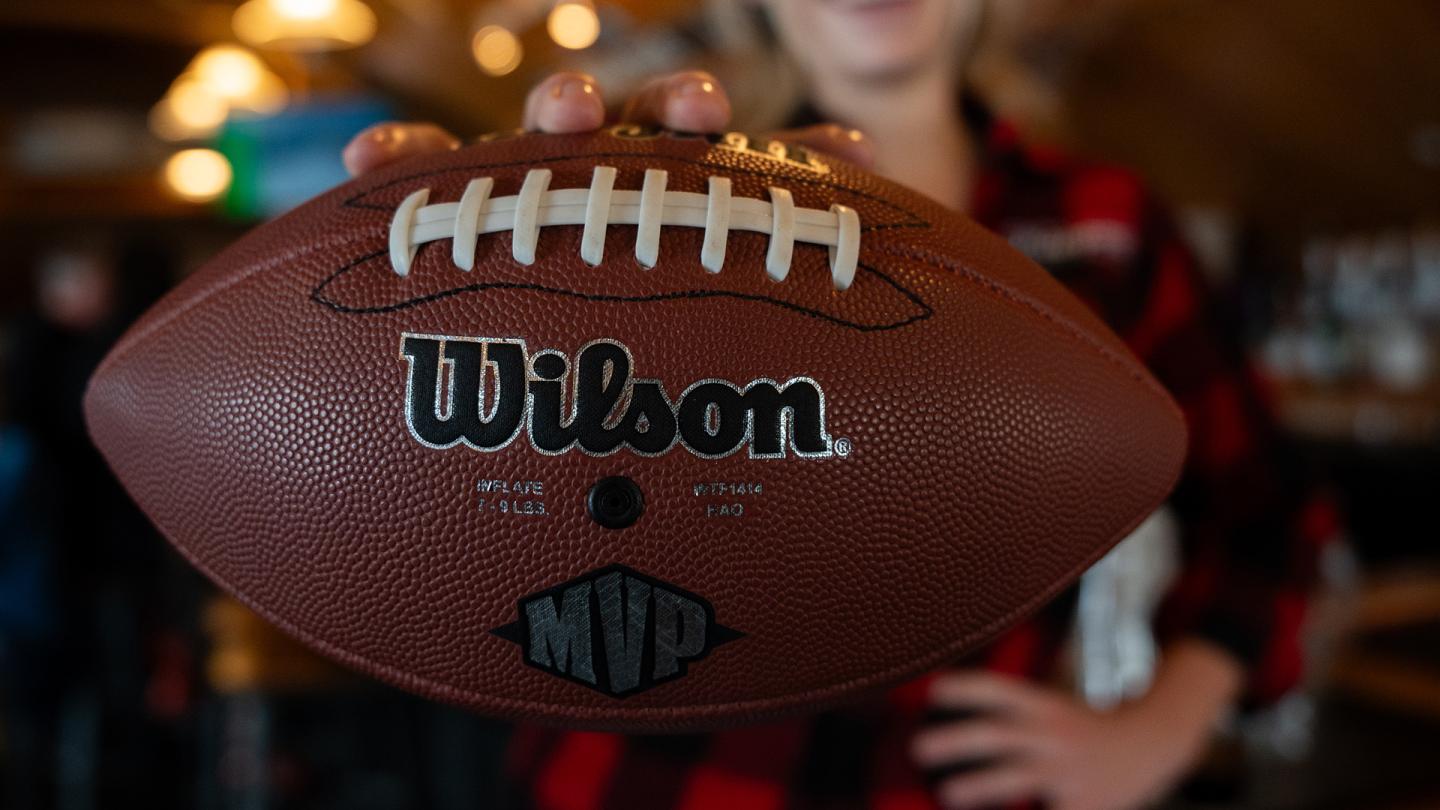 Wilson MVP football held in front of a blurred person in a sports store.