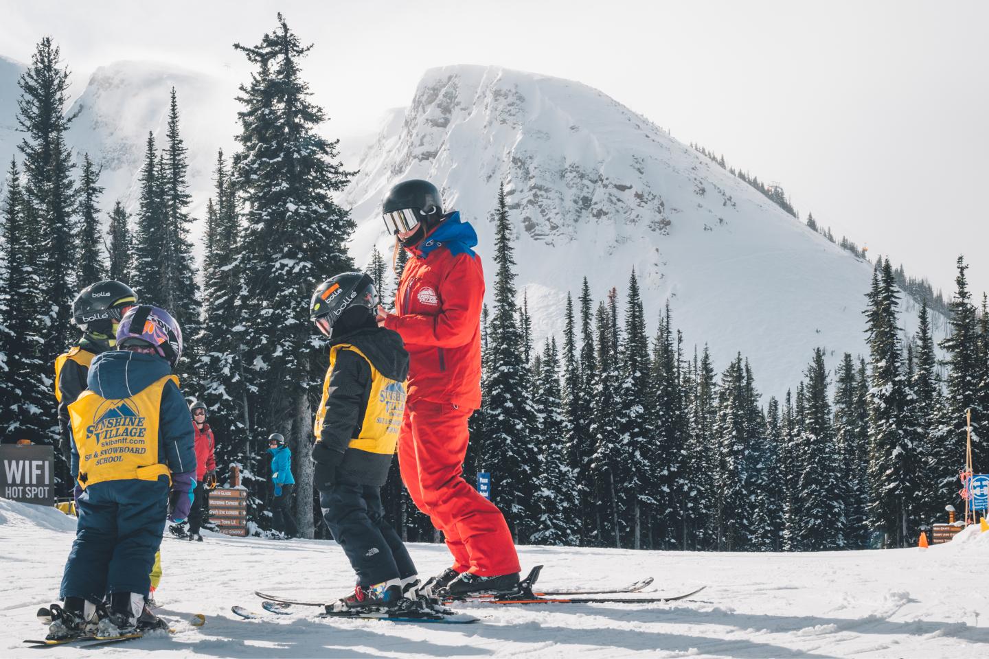 Three snowboarders in colorful gear stand on a snowy mountain slope.