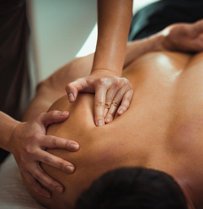 Massage therapist applying pressure to a client's bare back.