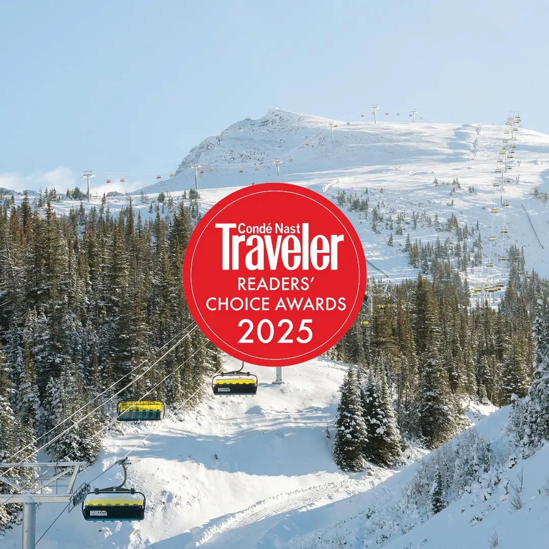 Snowy ski lift ascending through pine trees beneath a mountain, with 2025 Travel + Leisure award badge.